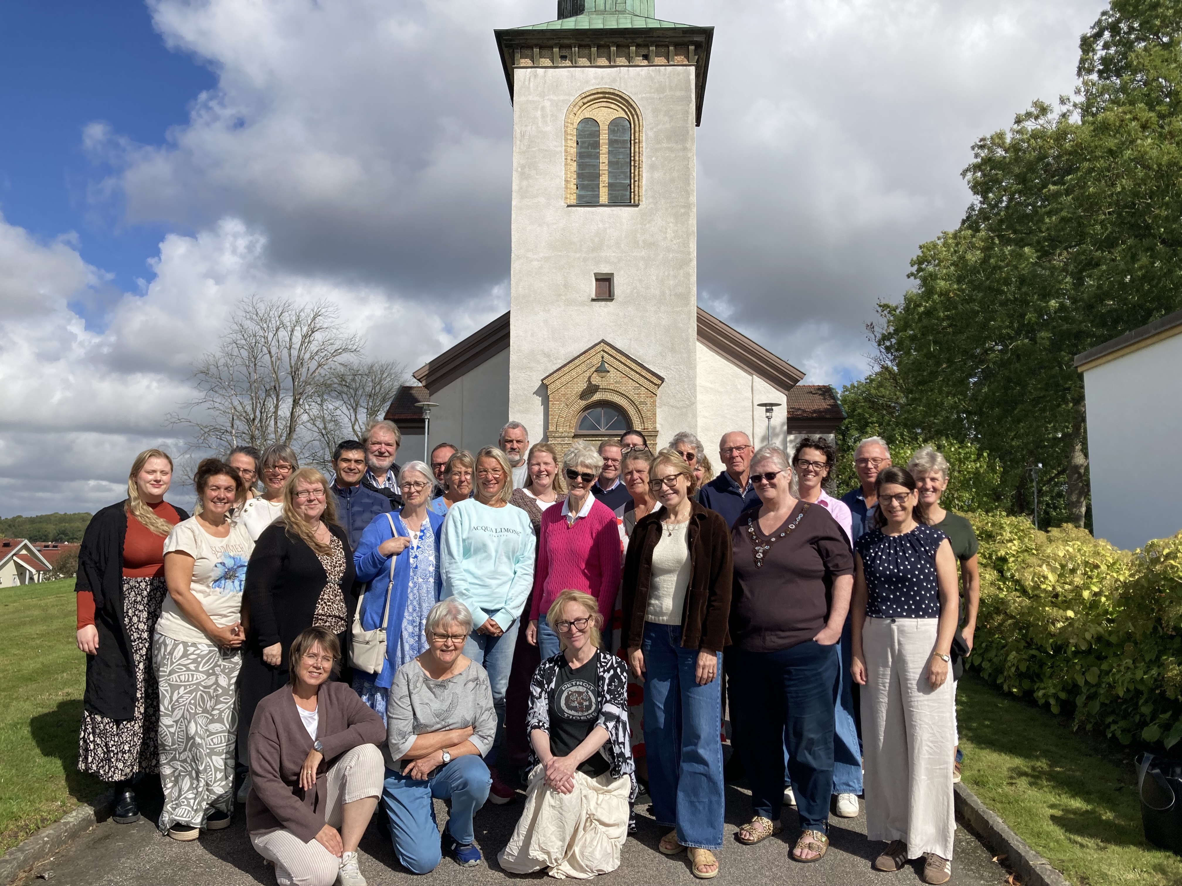En grupp människor står framför en vit stenkyrka