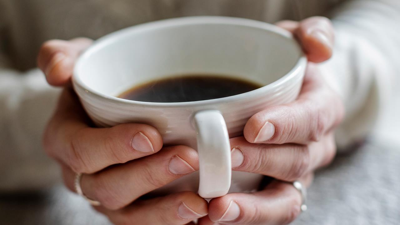 Kvinna med kopp kaffe i händerna
