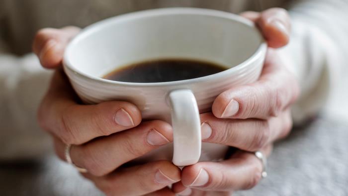 Kvinna med kopp kaffe i händerna