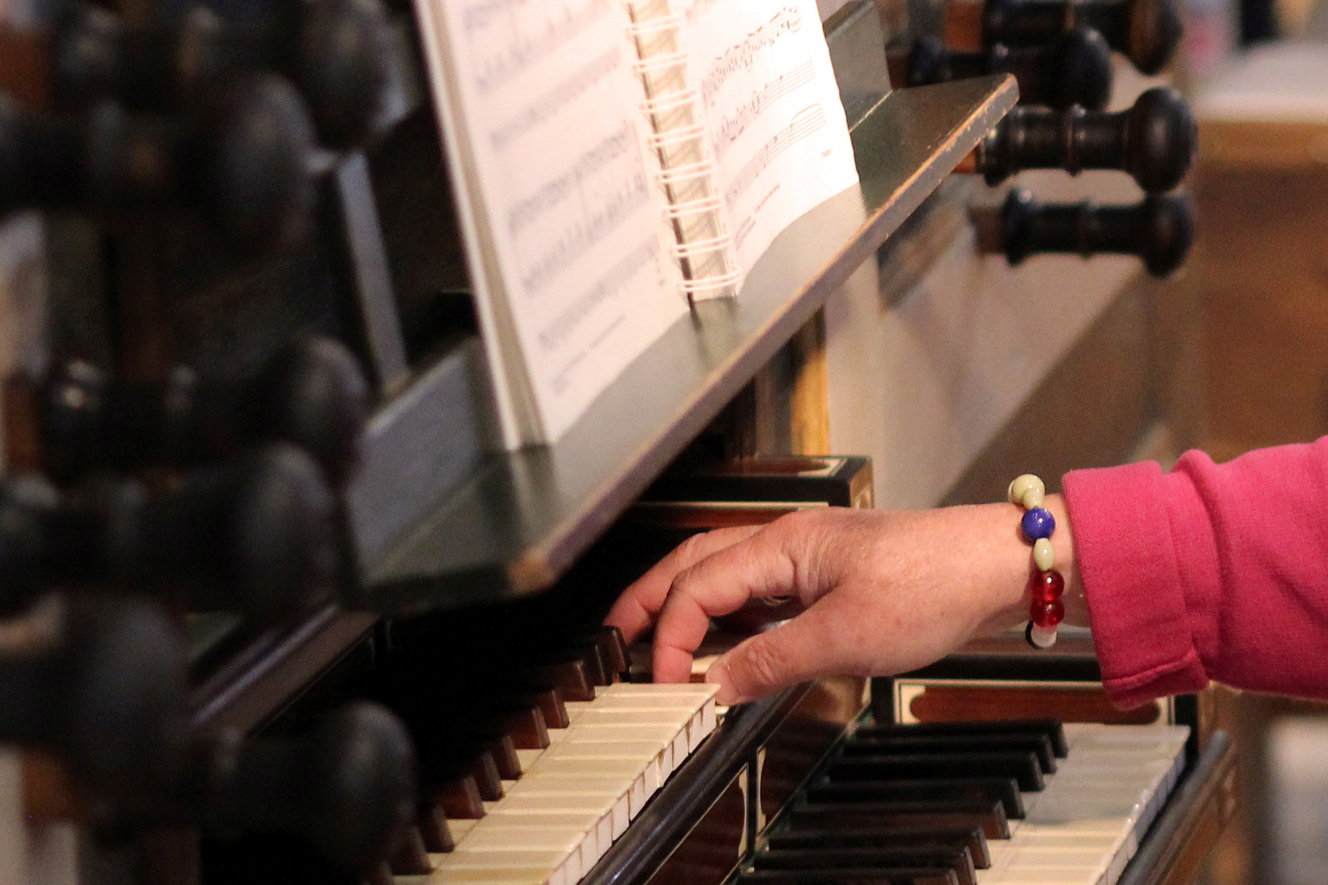 En hand med en frälsarkrans runt handleden spelar på orgeltangenter.