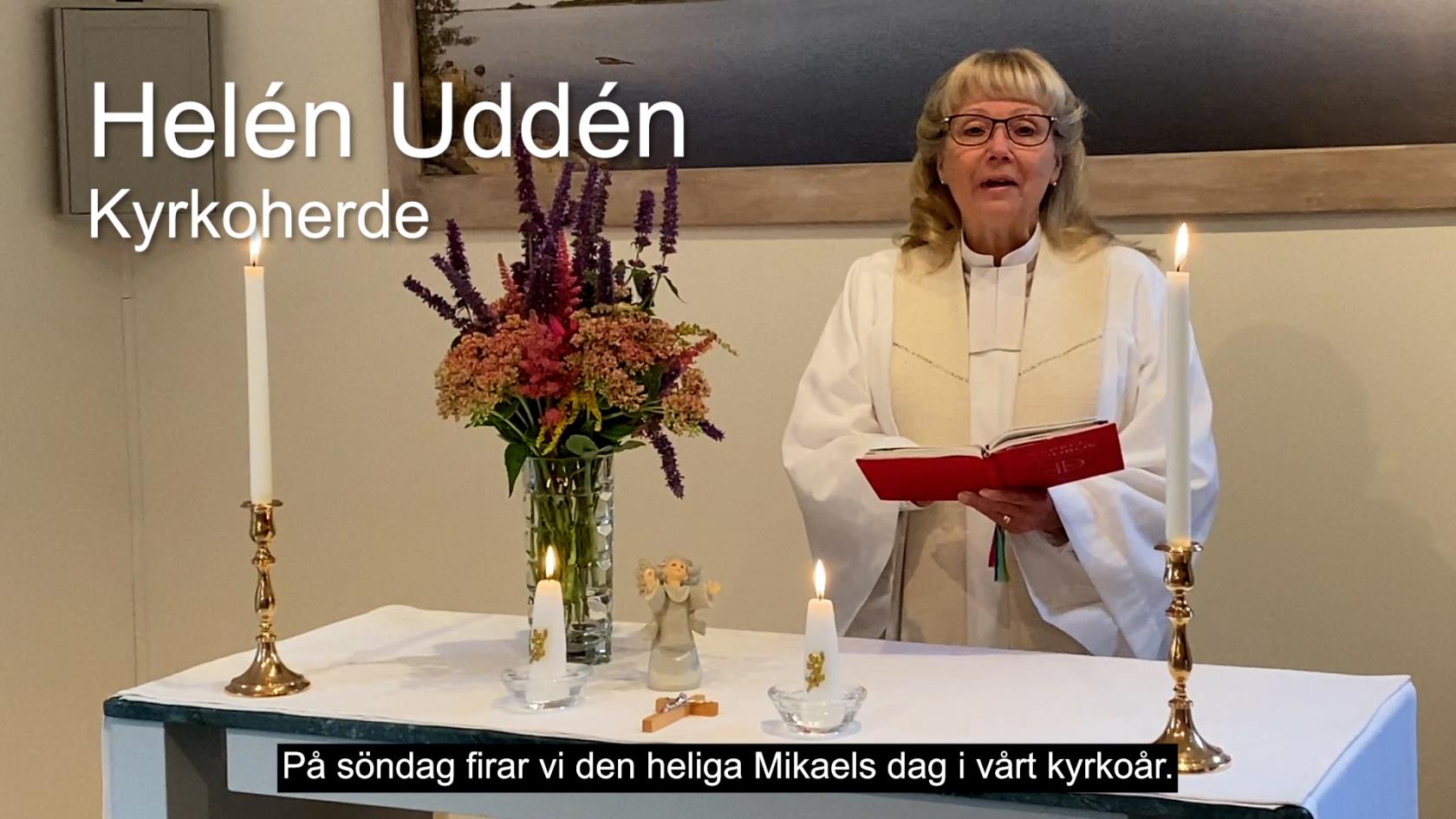 En kvinna i prästkläder står bakom ett altare. Hon har en bok i handen.
