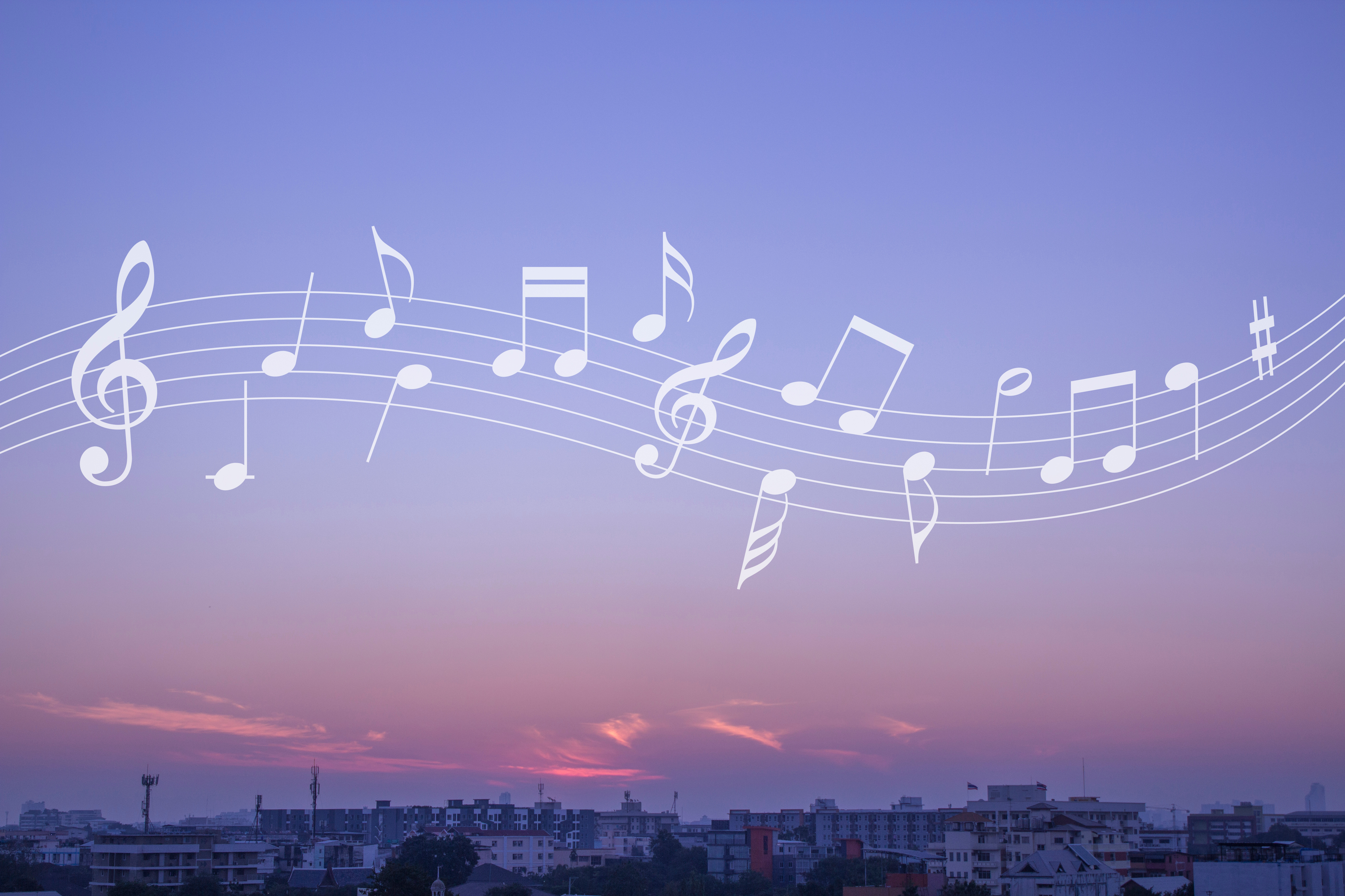 Ett band med noter flyter över himlen ovanför ett samhälle eller en stad. 