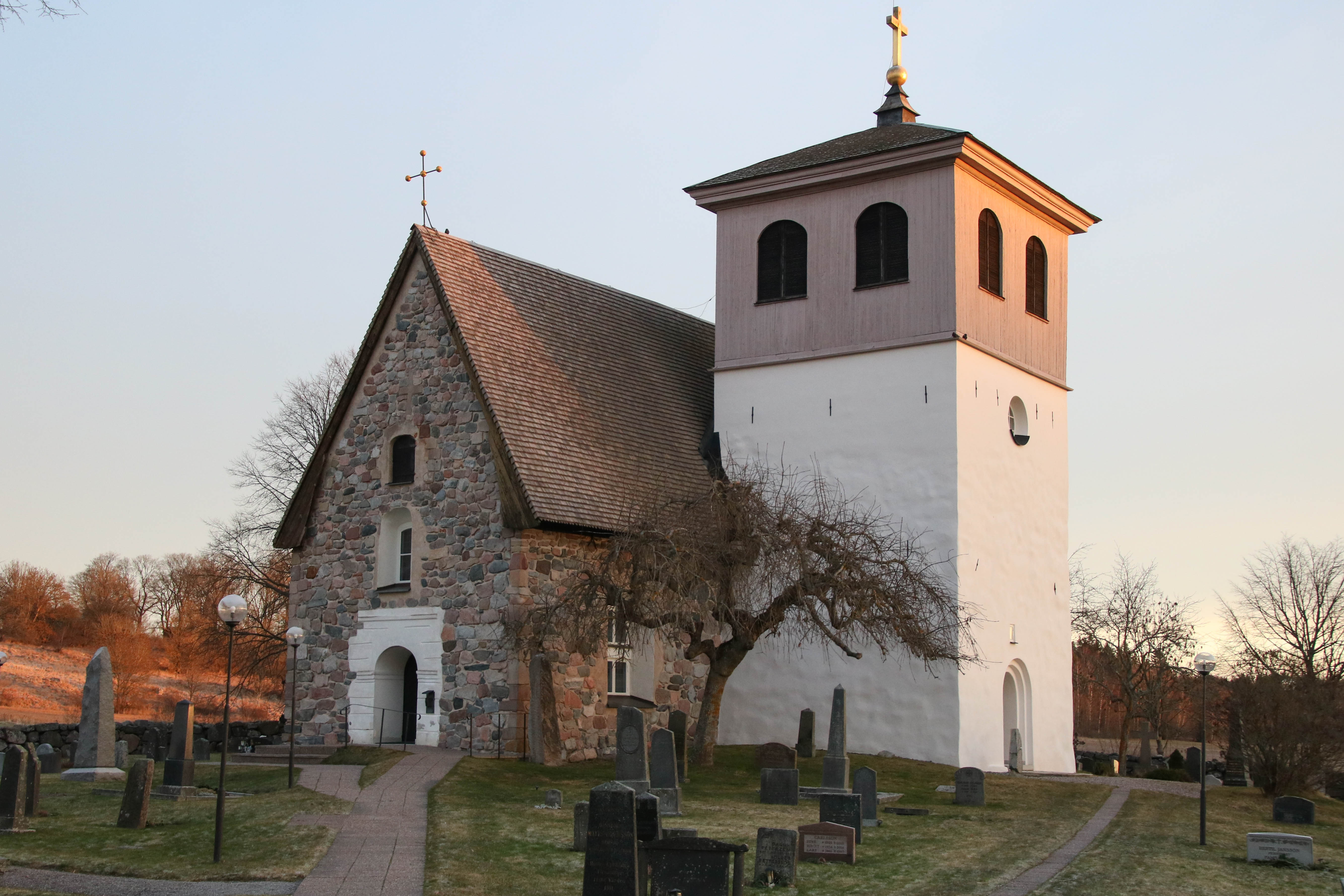 En liten tvåfärgad stenkyrka med ett klocktorn . 
