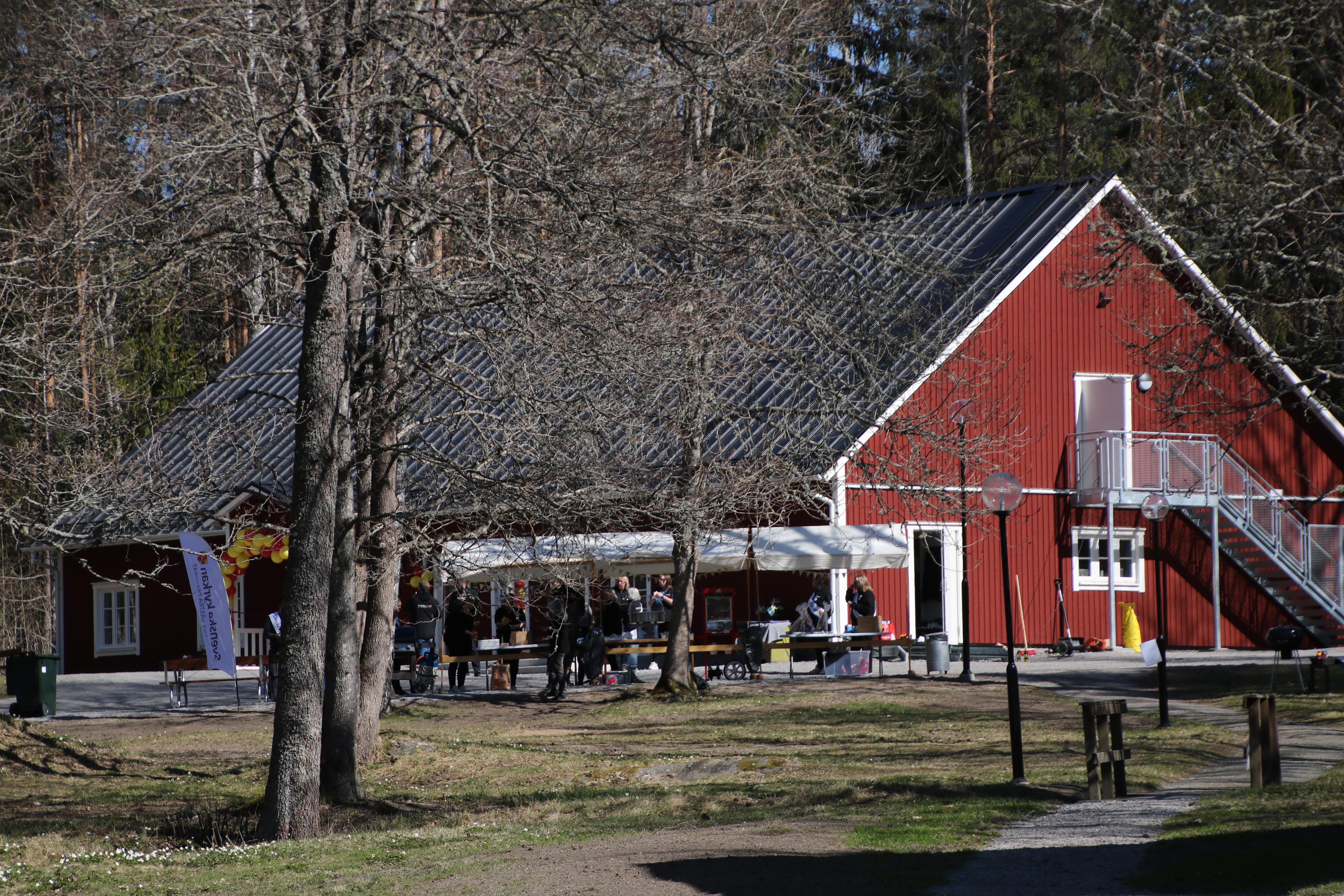 Gaveln på ett rött hus, framför huset torgstånd med människor