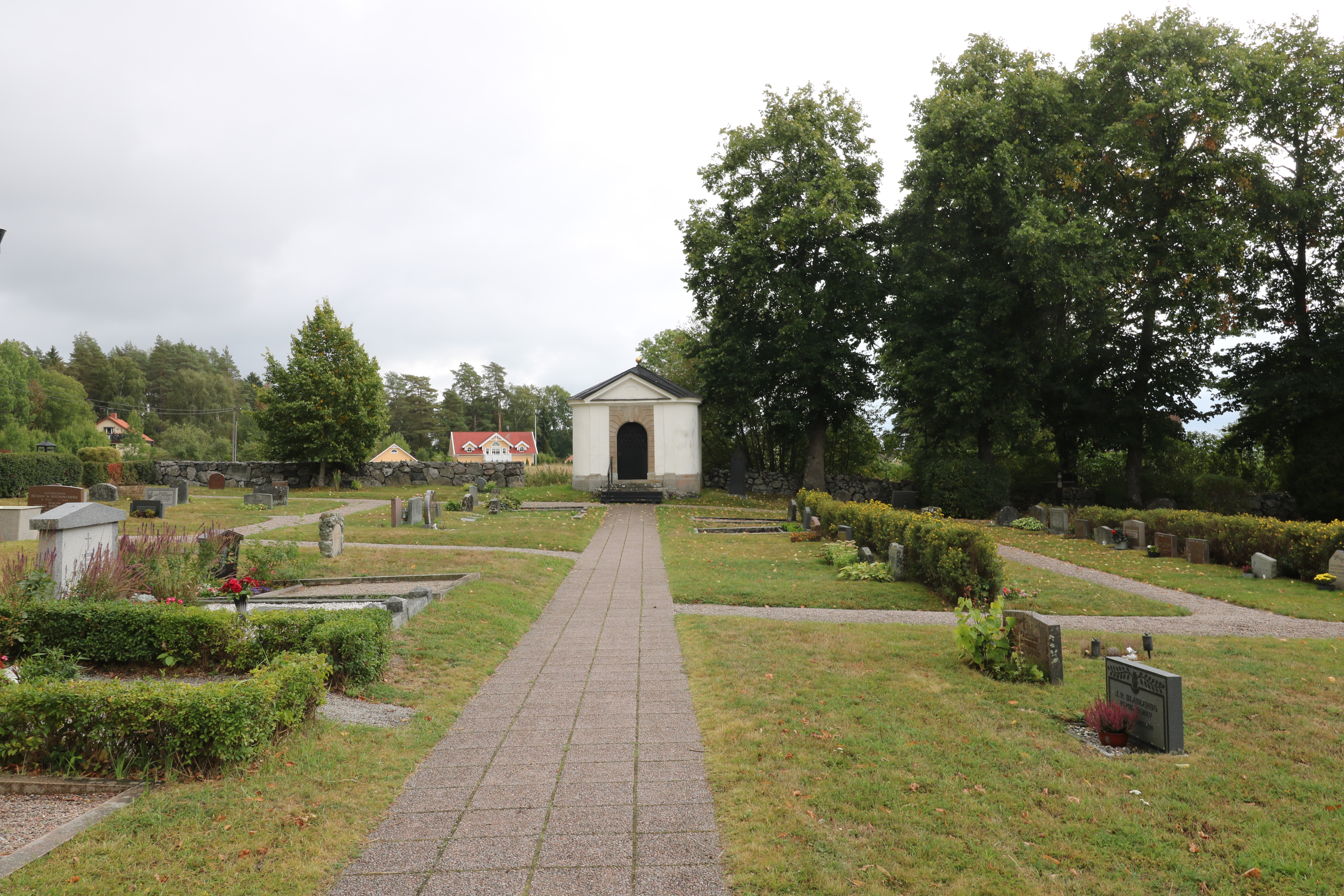 En kyrkogård med en lång gång som slutar i ett vitt litet putsat hus, ett gravkor.