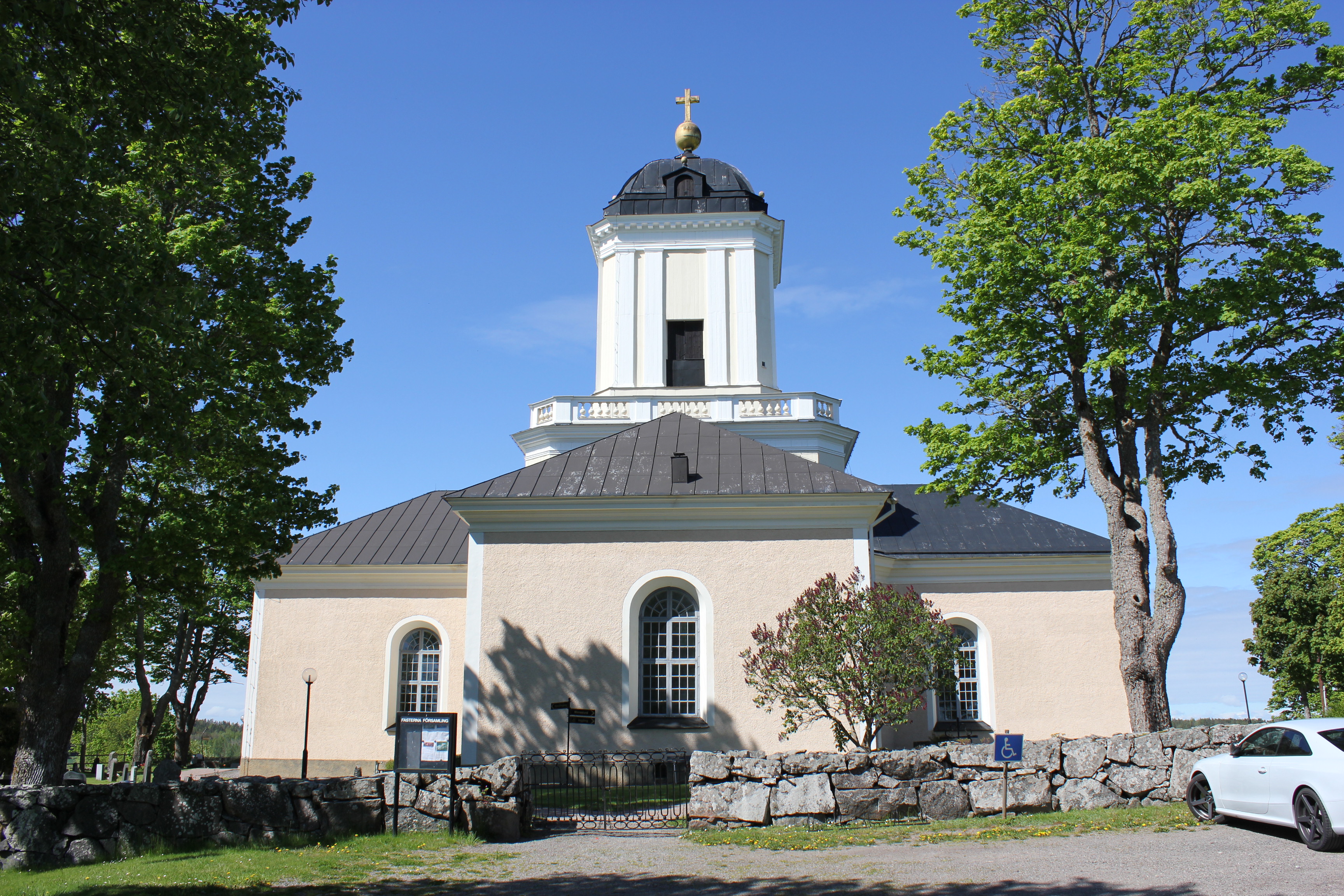 En stor, ljus, putsad stenkyrka med ett högt torn. 