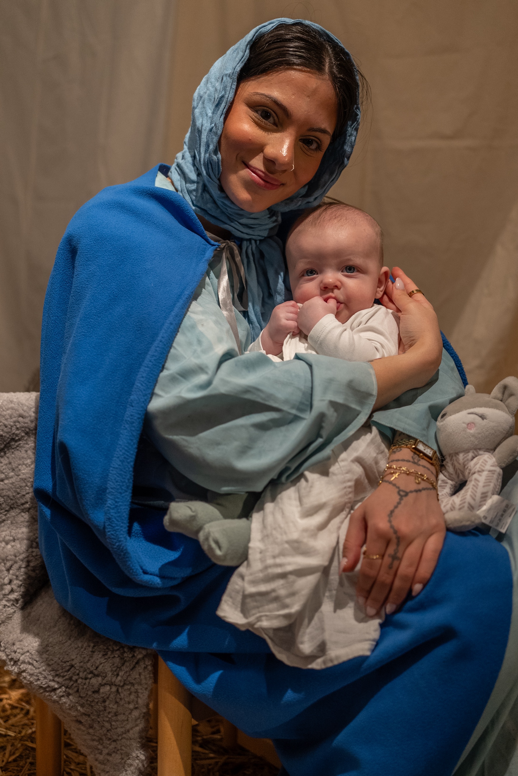 En flicka utklädd till Maria håller en bebis i famnen.