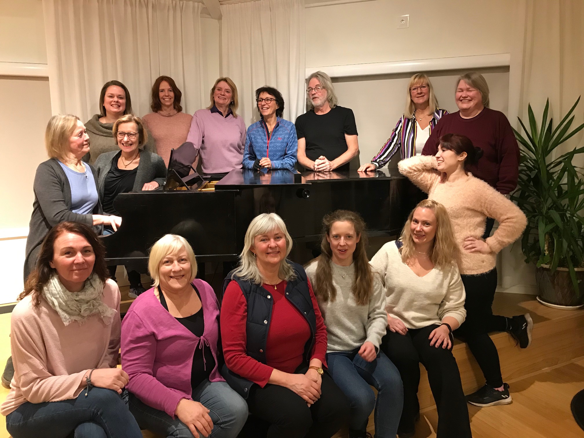 Körmedlemmarna i Nova Gospel är samlade runt en flygel tillsammans med körledare Ingrid Jilderin