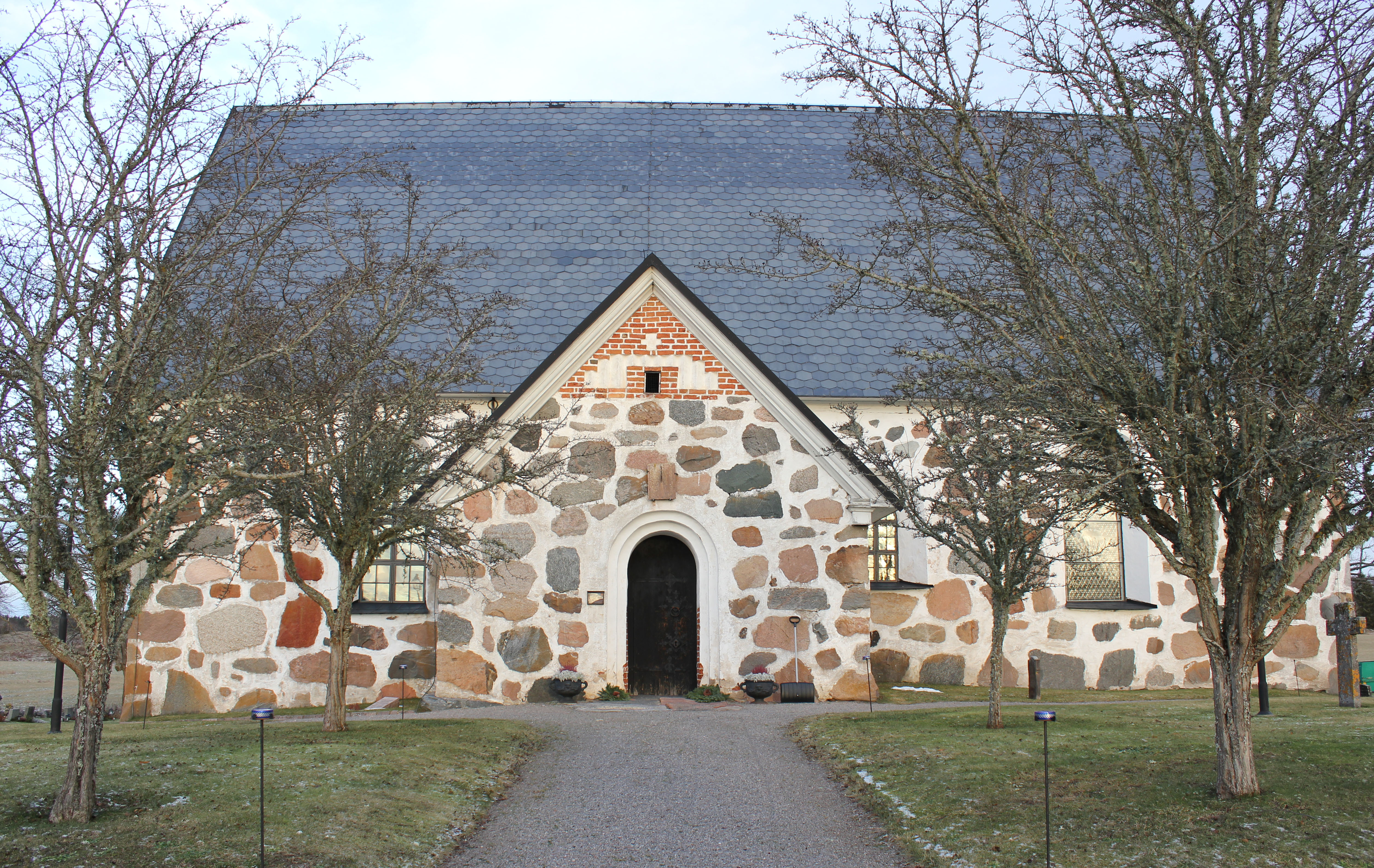 En stenmkyrka med grått tak sedd framifrån.