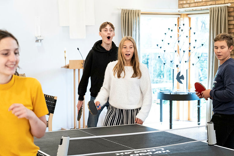 Glada ungdomar runt ett pingisbord