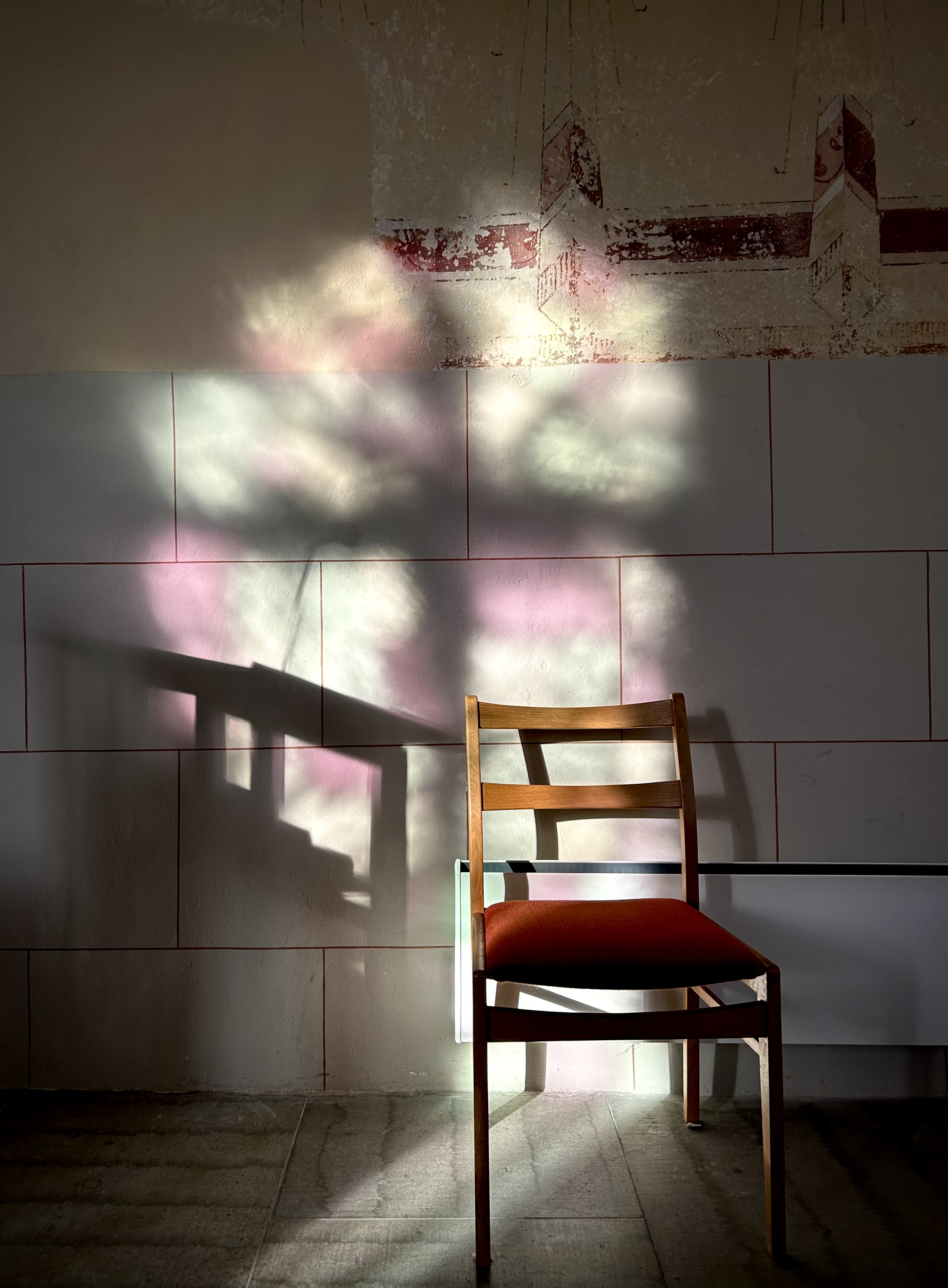 Ljus från flerfärgat kyrkfönster på vägg och stol