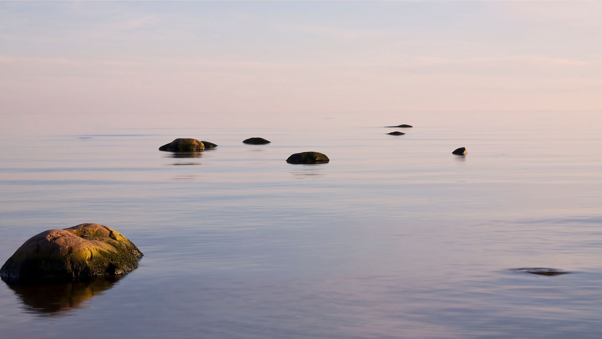 Stilla hav i soluppgång eller solnedgång med några stenar som sticker upp
