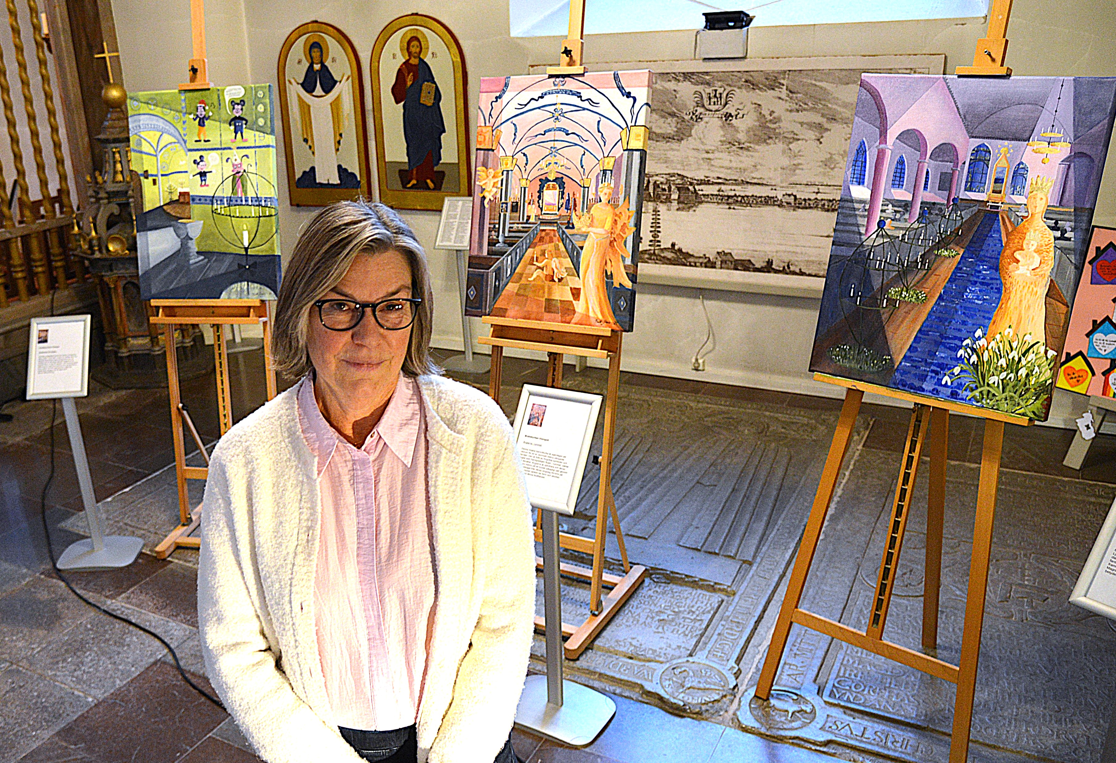 En kvinna står framför tre tavlor