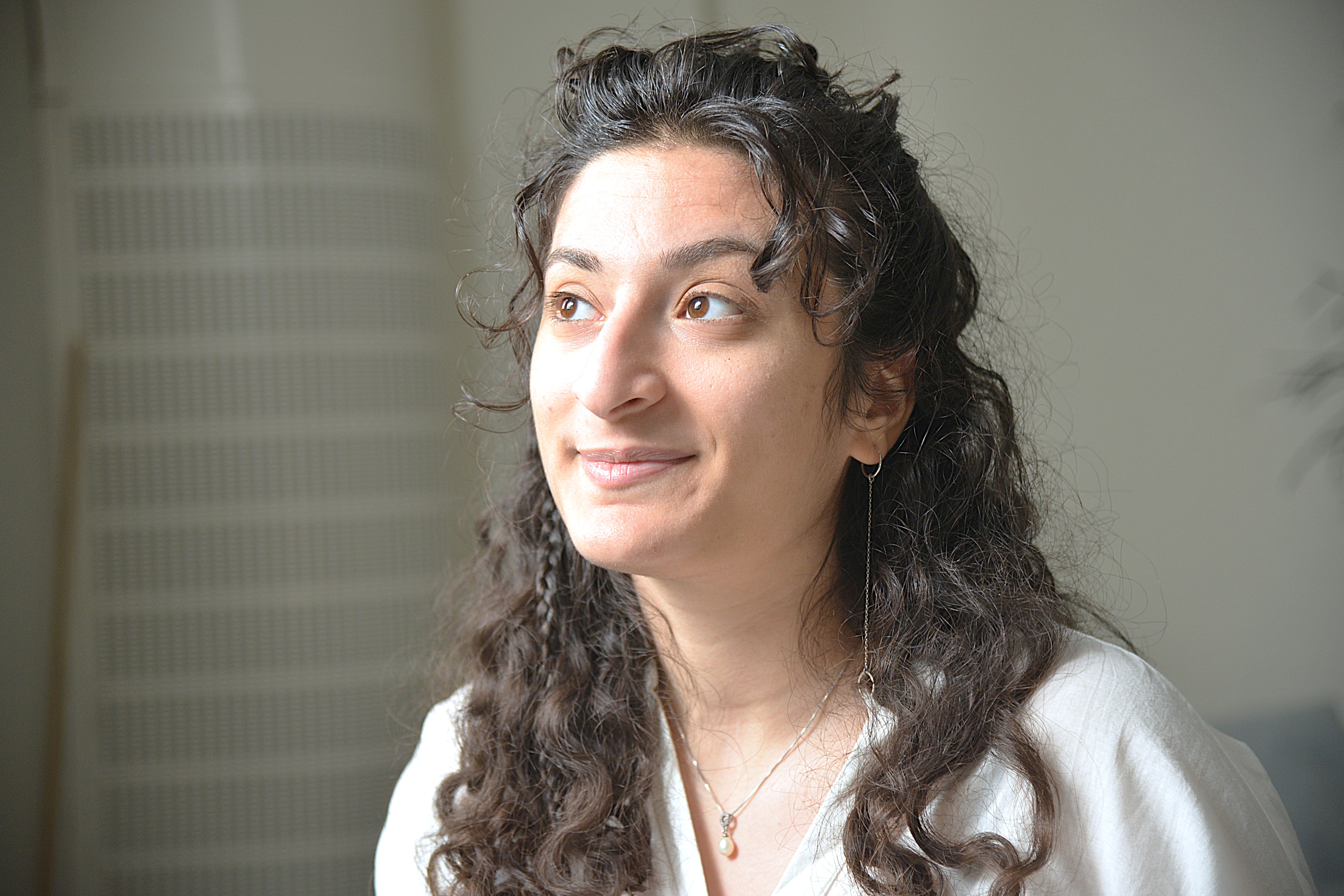 Porträtt av en kvinna med mörkt hår i vit blus