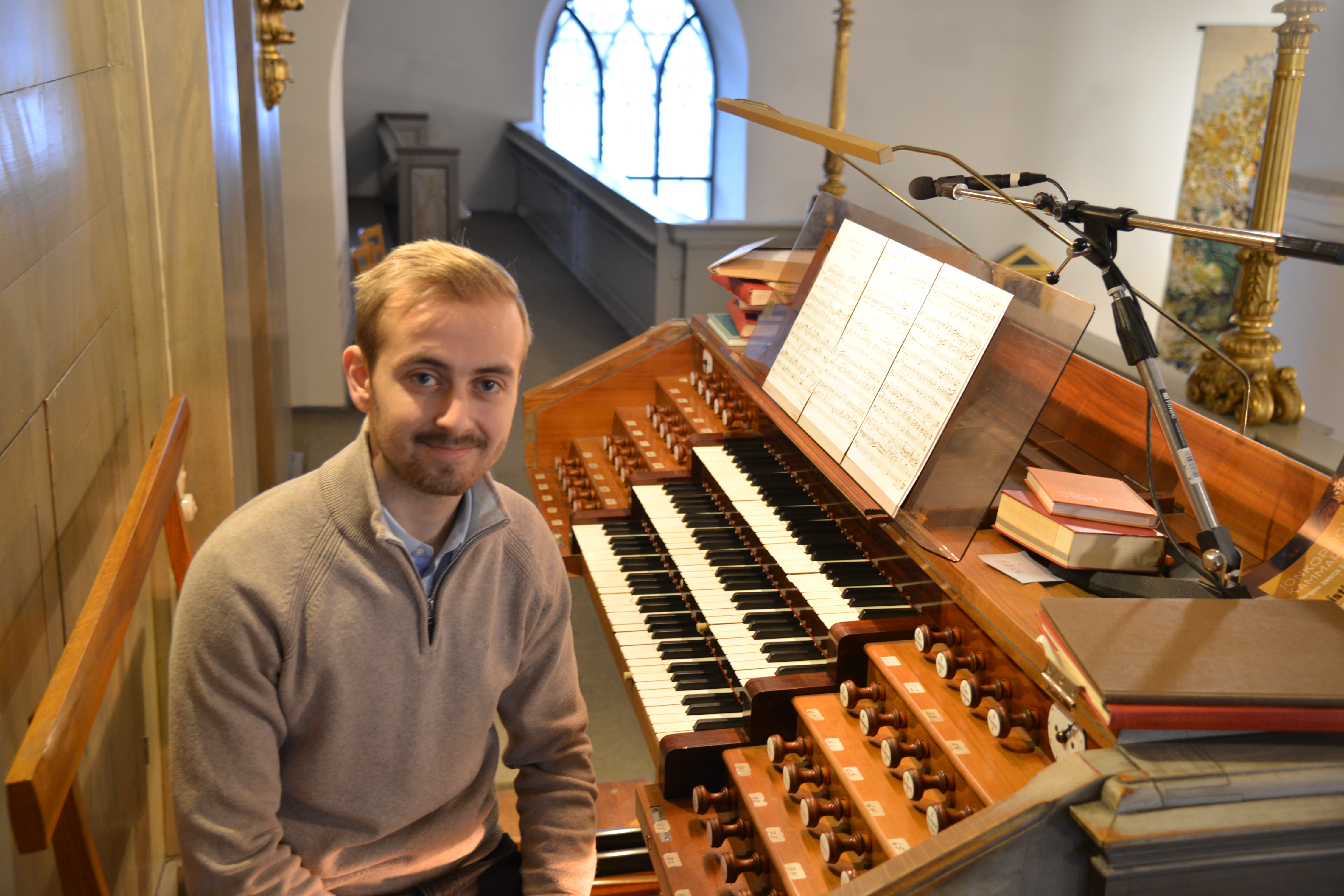En man sitter vid bänken till en orgel