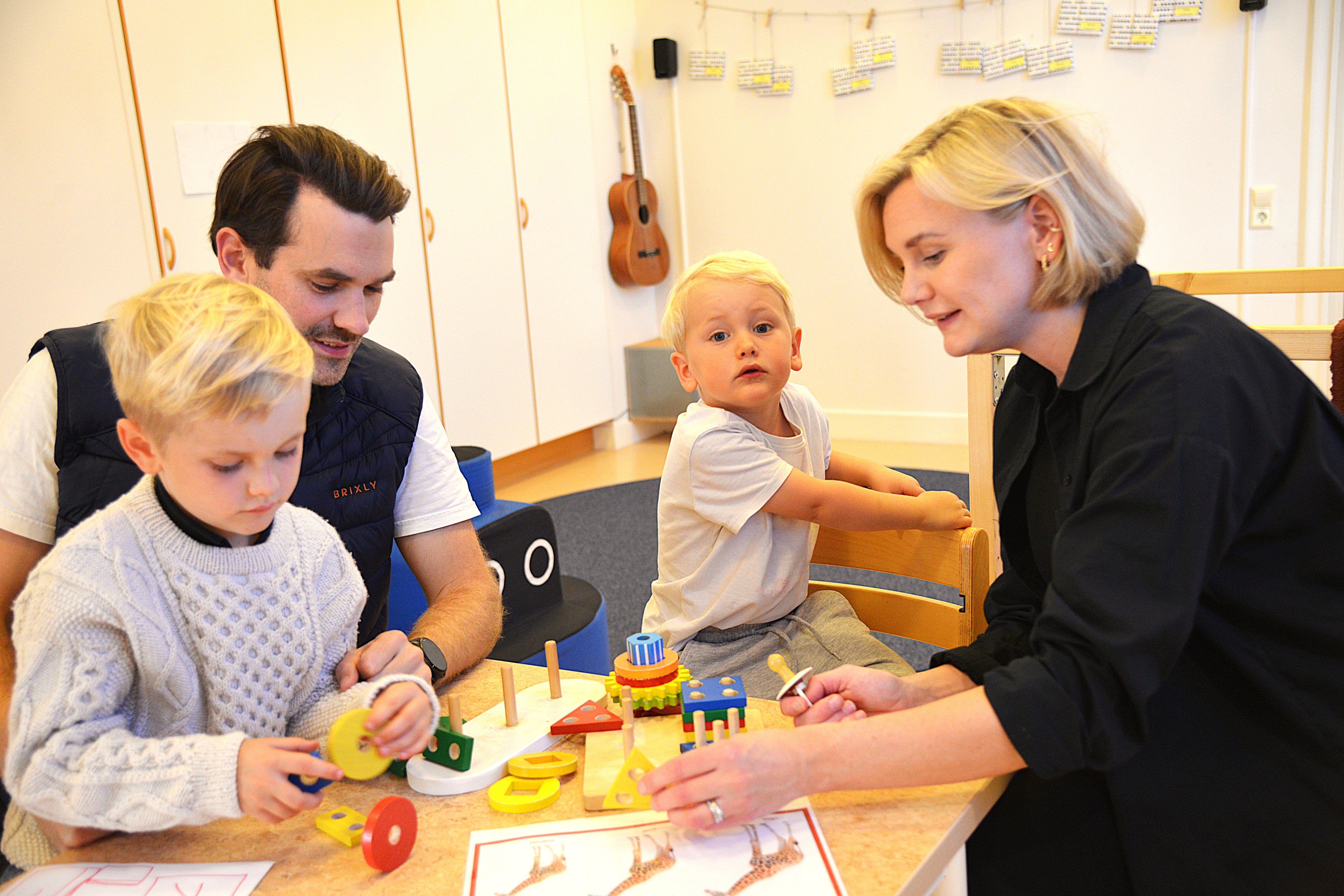 En familj sitter vid ett bord och leker