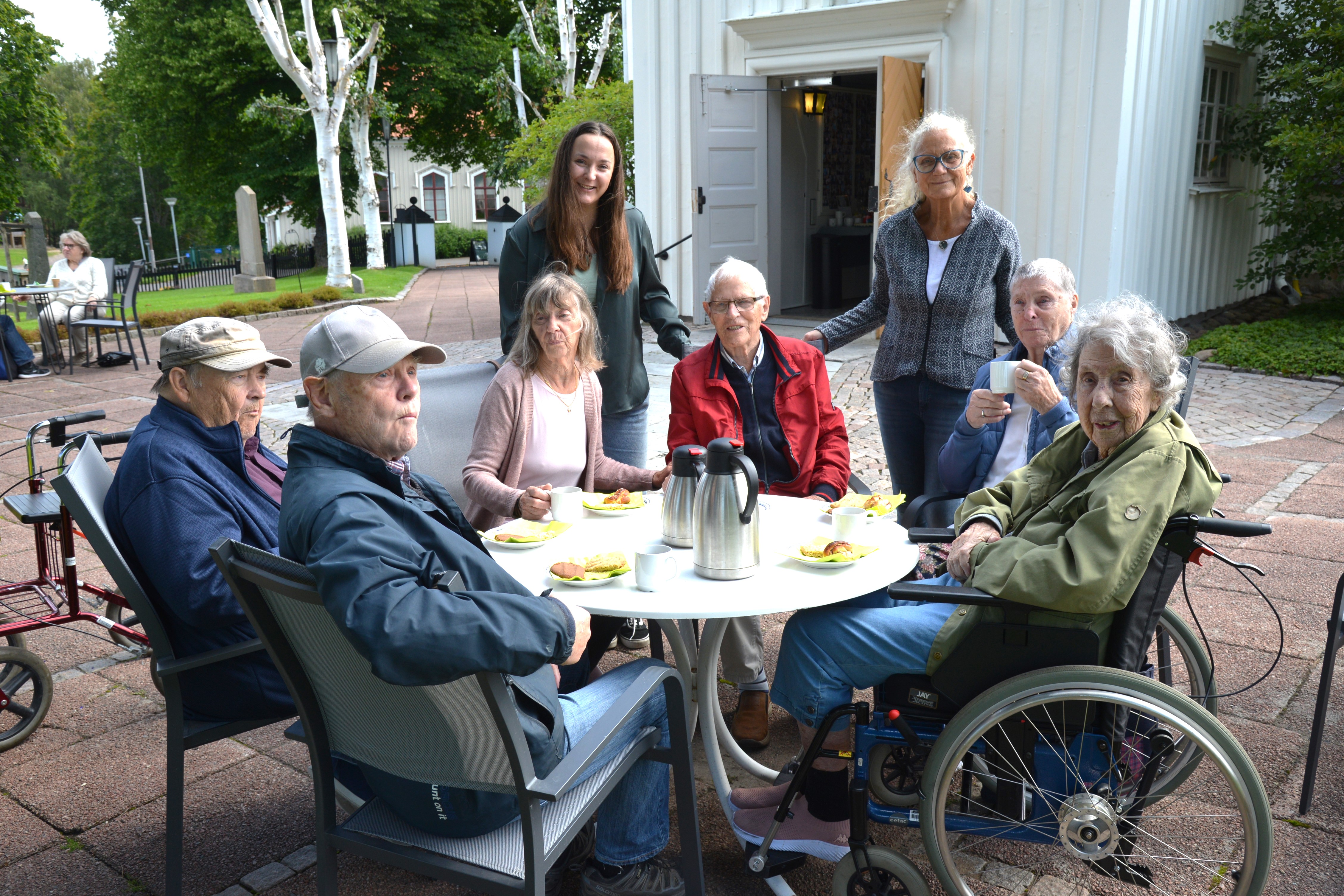 En grupp människor sitter och fikar runt ett bord