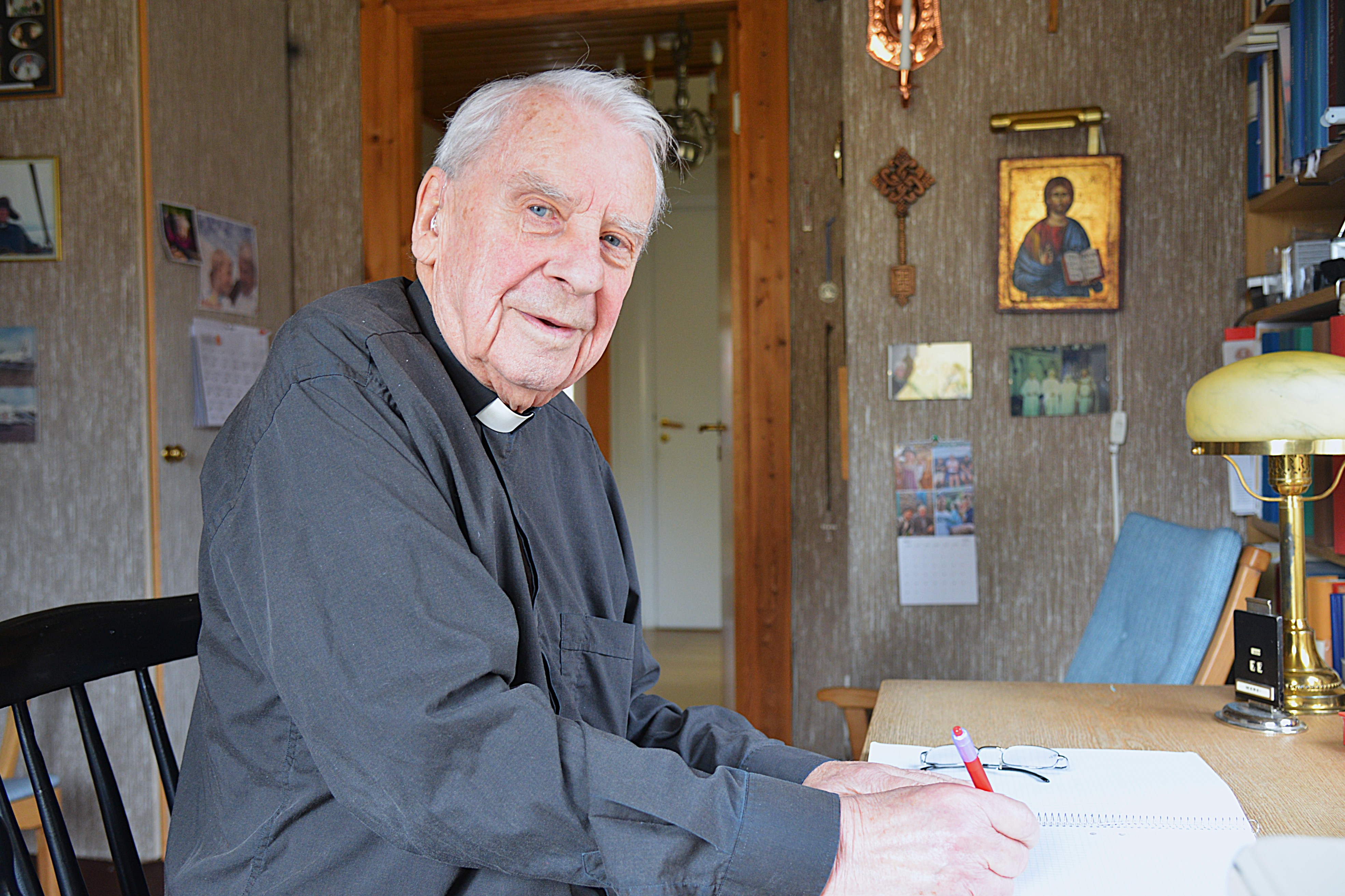 En man i prästkläder sitter vid ett skrivbord