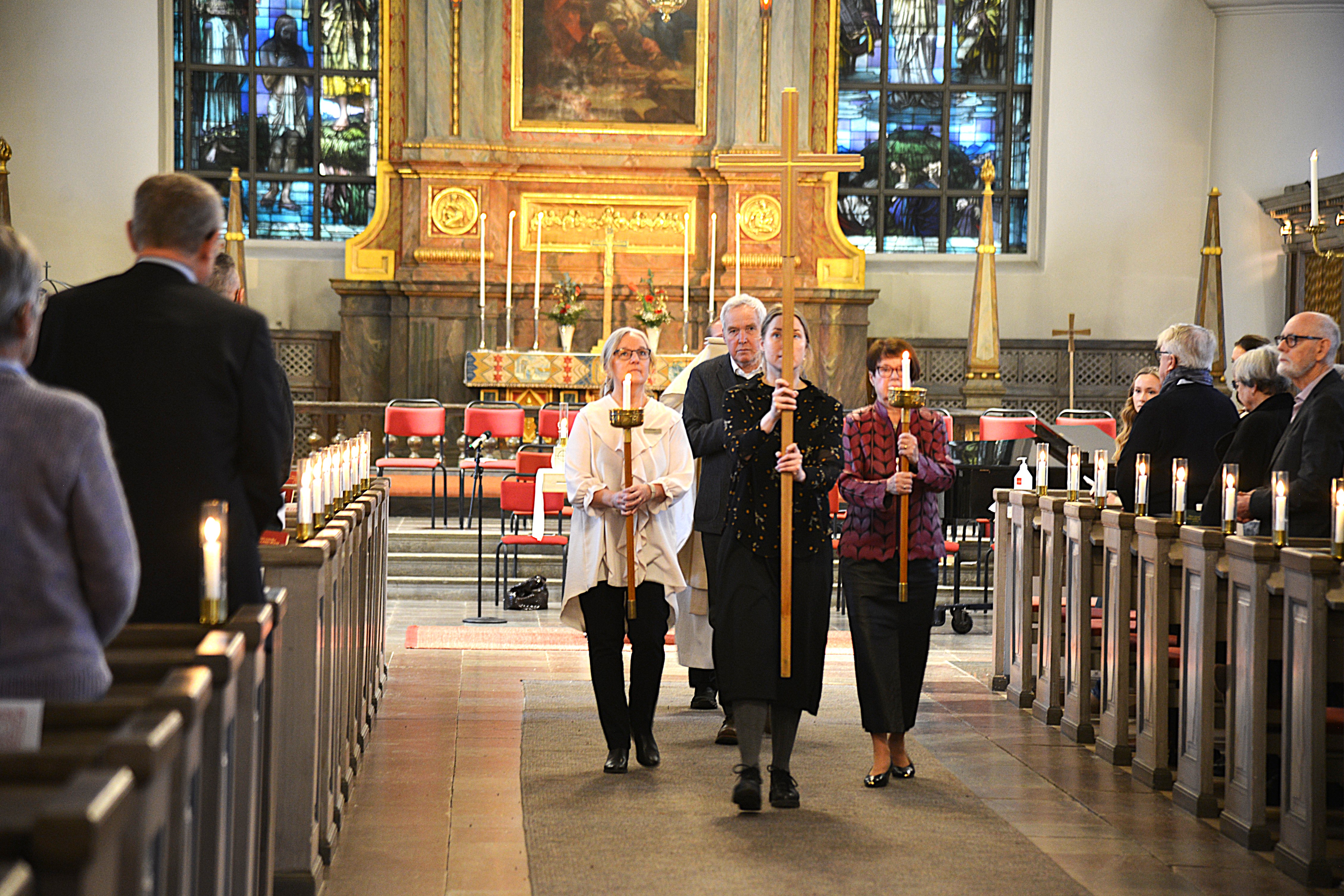 Människor bär ett kors i ett kyrkorum