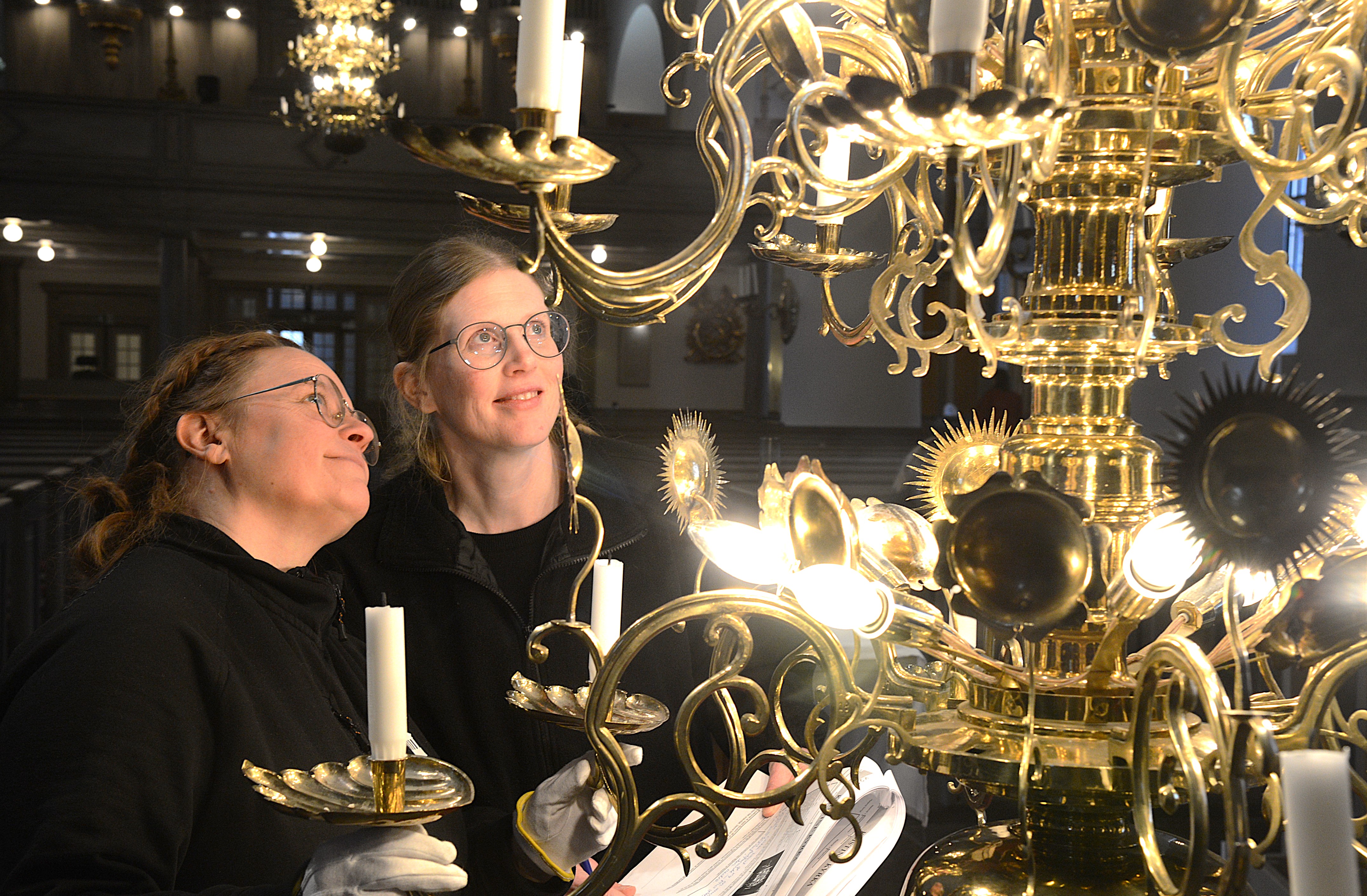 Två kvinnor står vid en ljuskrona