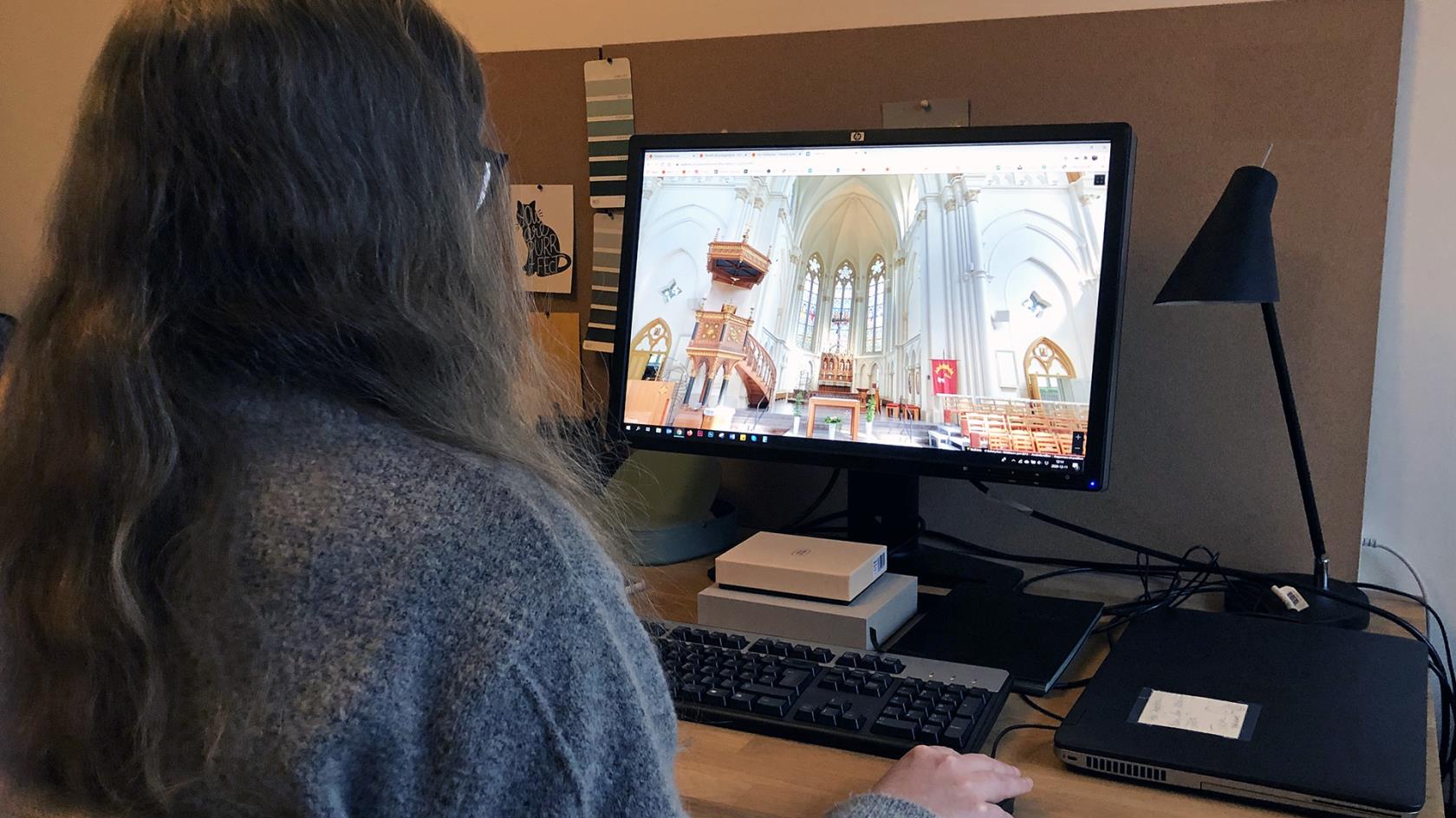 Kvinna sitter framför datorskärm som visar en virtuell rundtur av Sofiakyrkan.