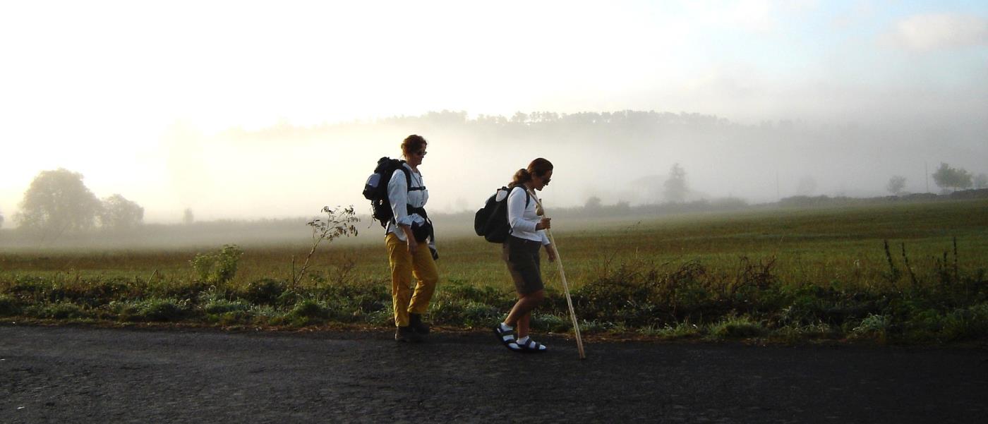 två personer som pilgrimsvandrar längs en väg