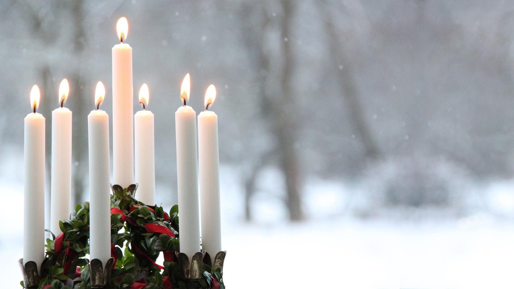 En luciakrona med tända levande ljus står och lyser i snön.