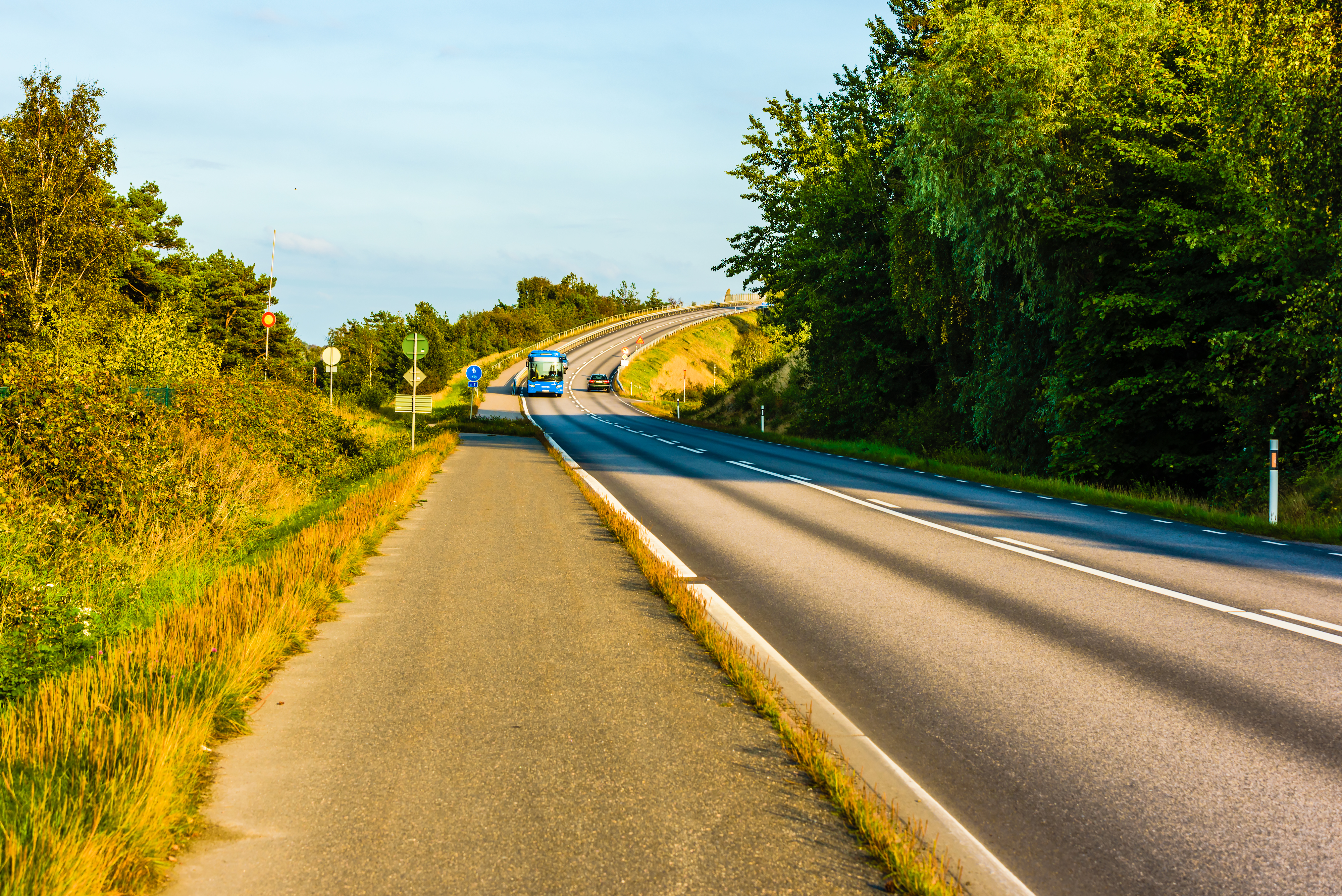En blå buss åker på en väg i Sverige under sommaren.
