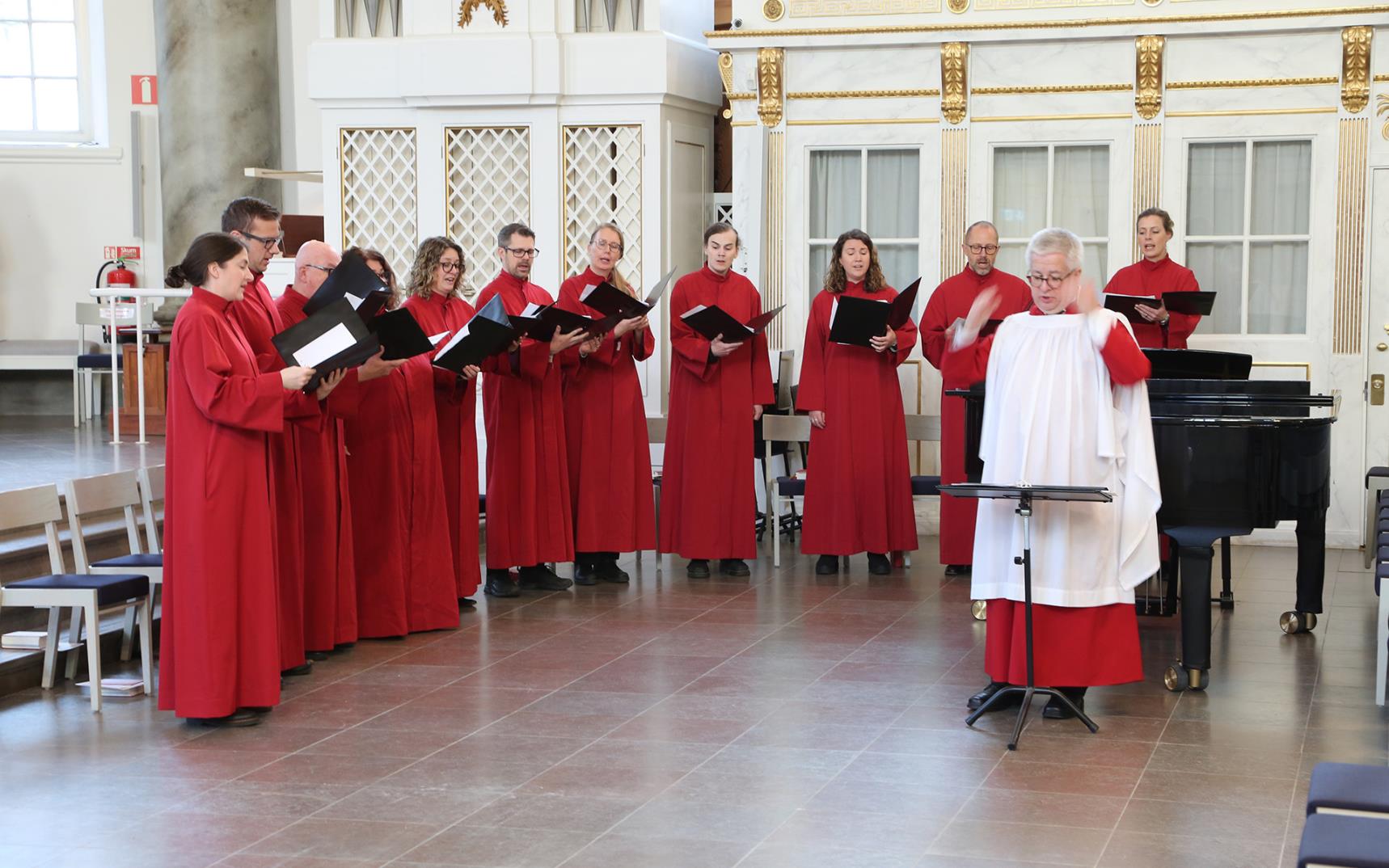 Gustavi vokalensemble i röda kåpor.