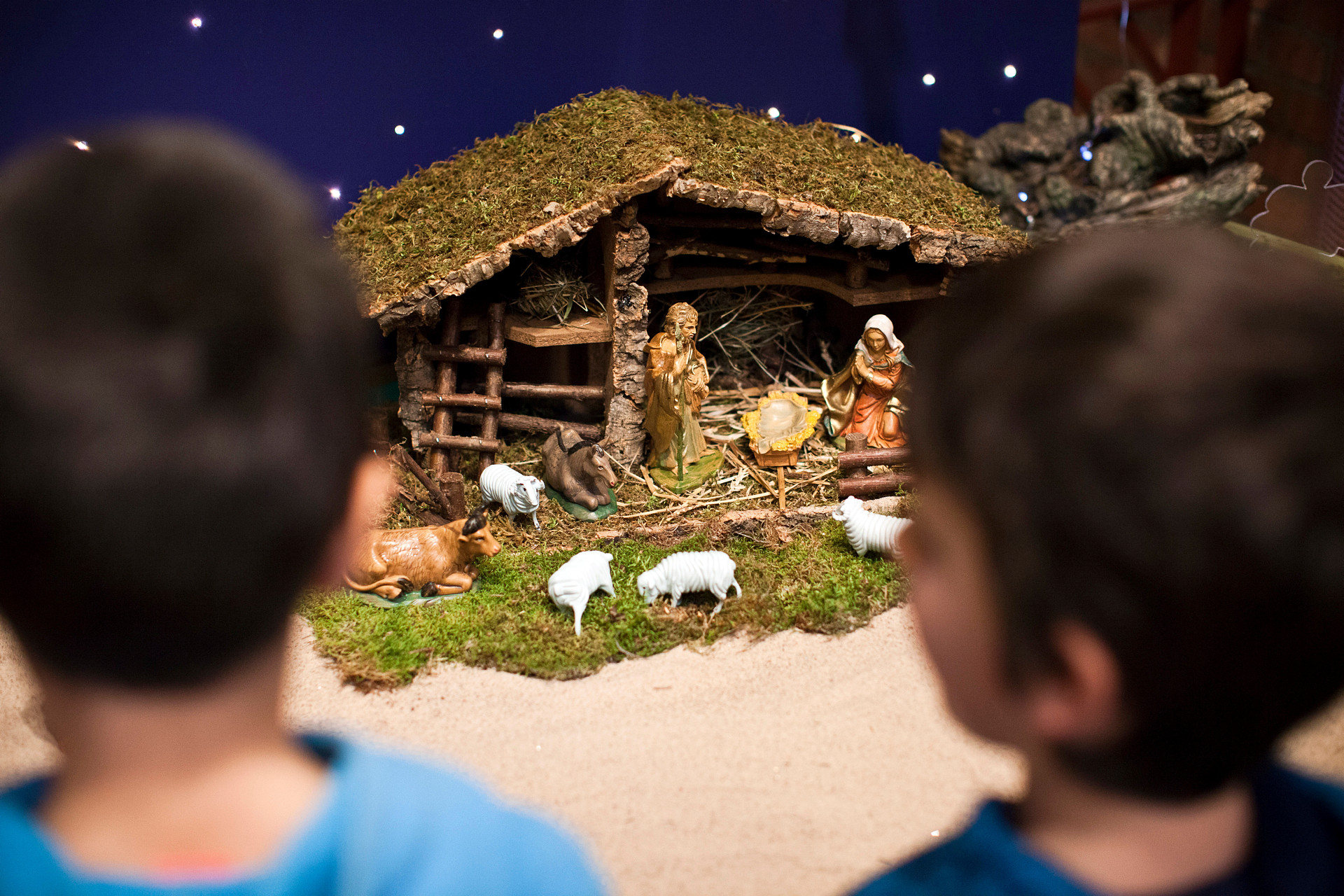 Barn i förgrunden som tittar på en julkrubba. 