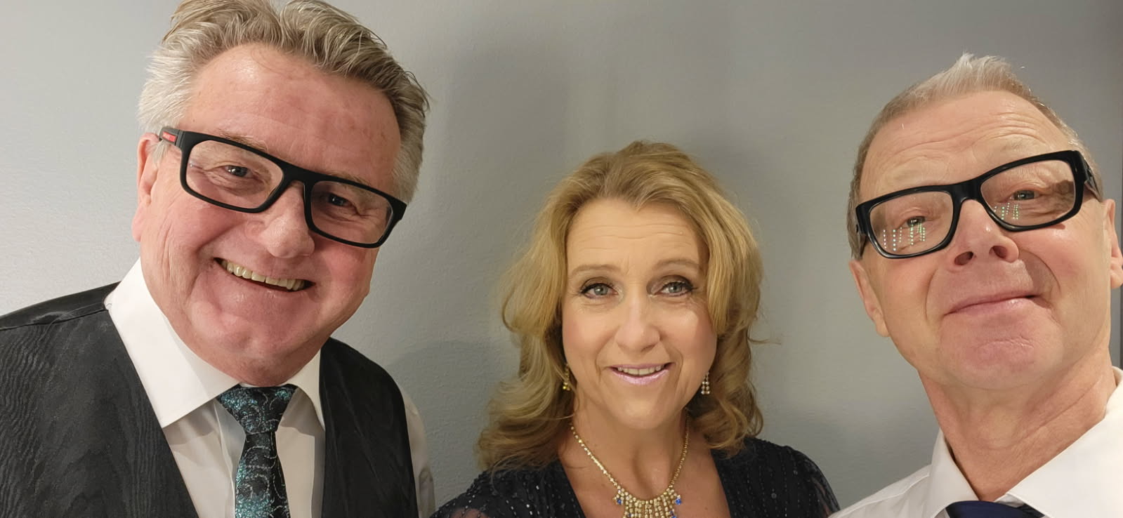Tre personer poserar glatt för kameran.