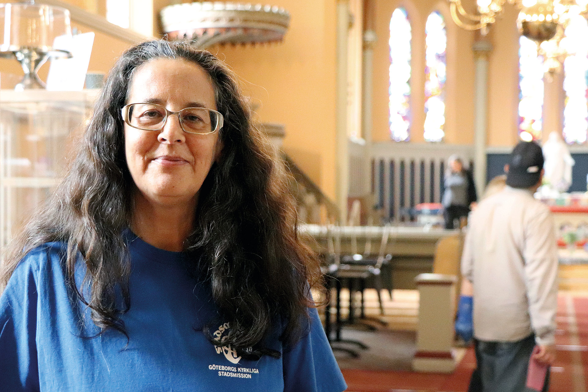 En kvinna i blå t-shirt står inne i kyrkan.