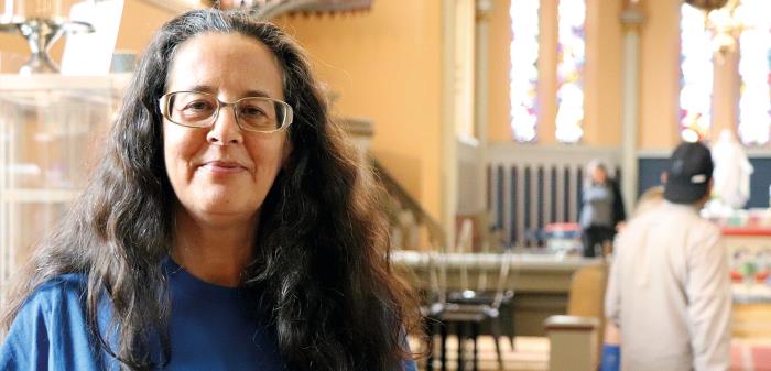 En kvinna i blå t-shirt står inne i kyrkan.
