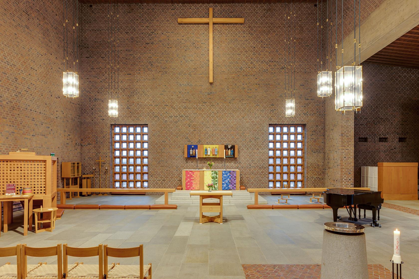 Koret med altaret i mitten omgärdat av två stora fönster och ett t-format kors längst uppe vid taket.