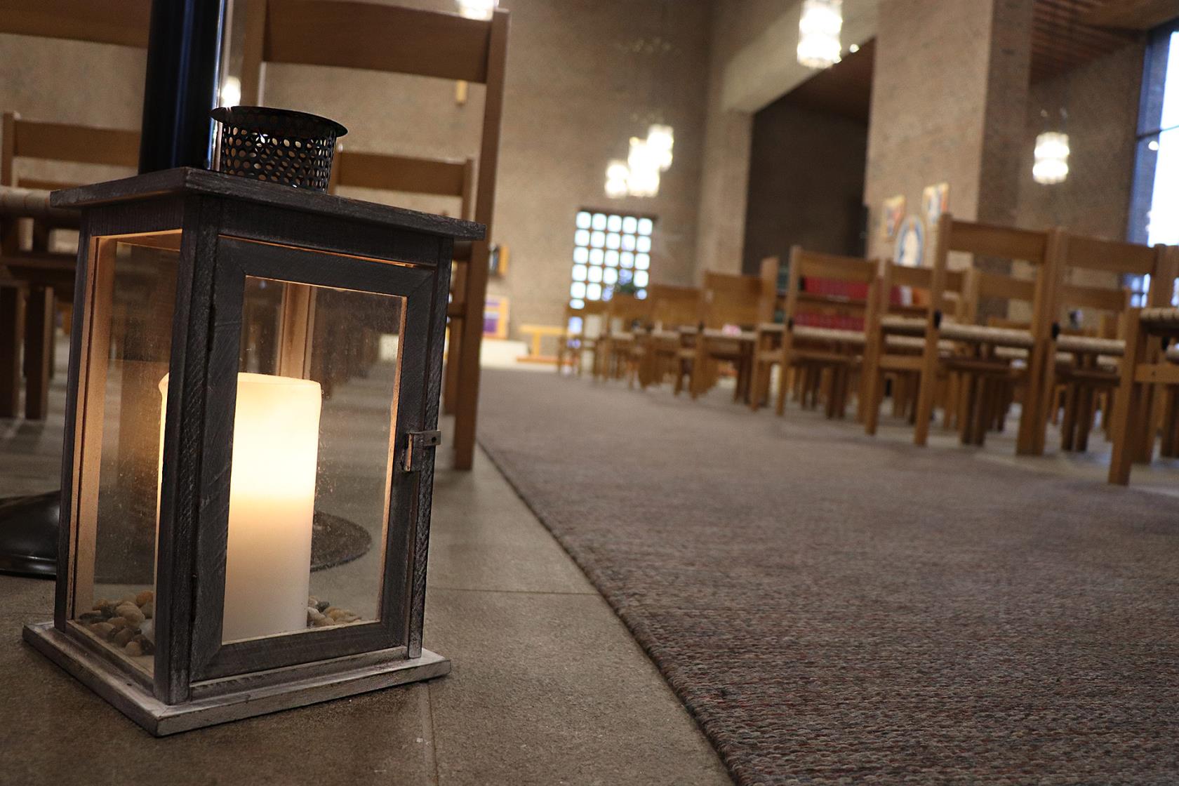 En ljuslykta står tänd invid mittgången i Härlanda kyrka.
