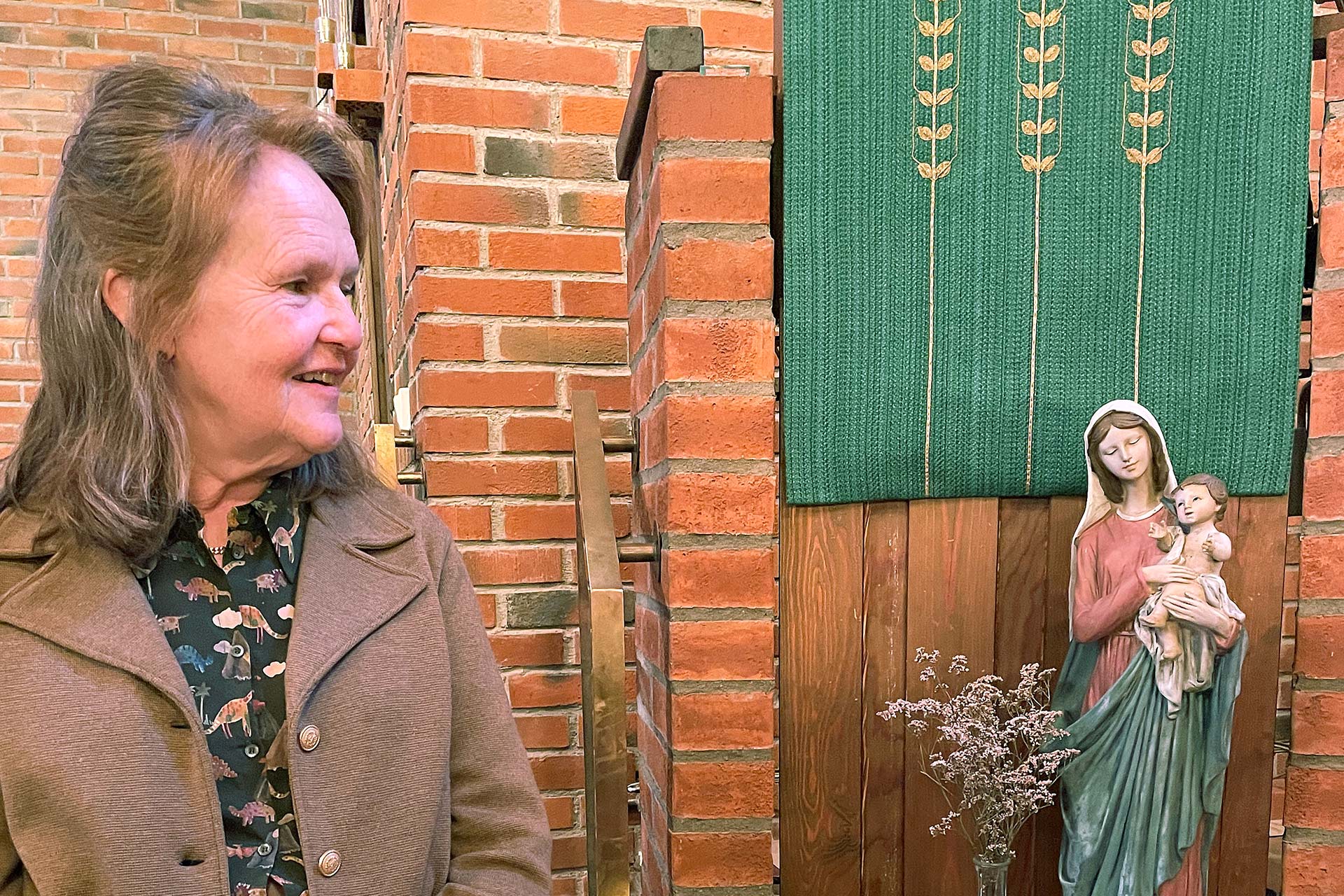 Ett foto på Marie som tittar på en Mariastaty i ett kyrkorum. 