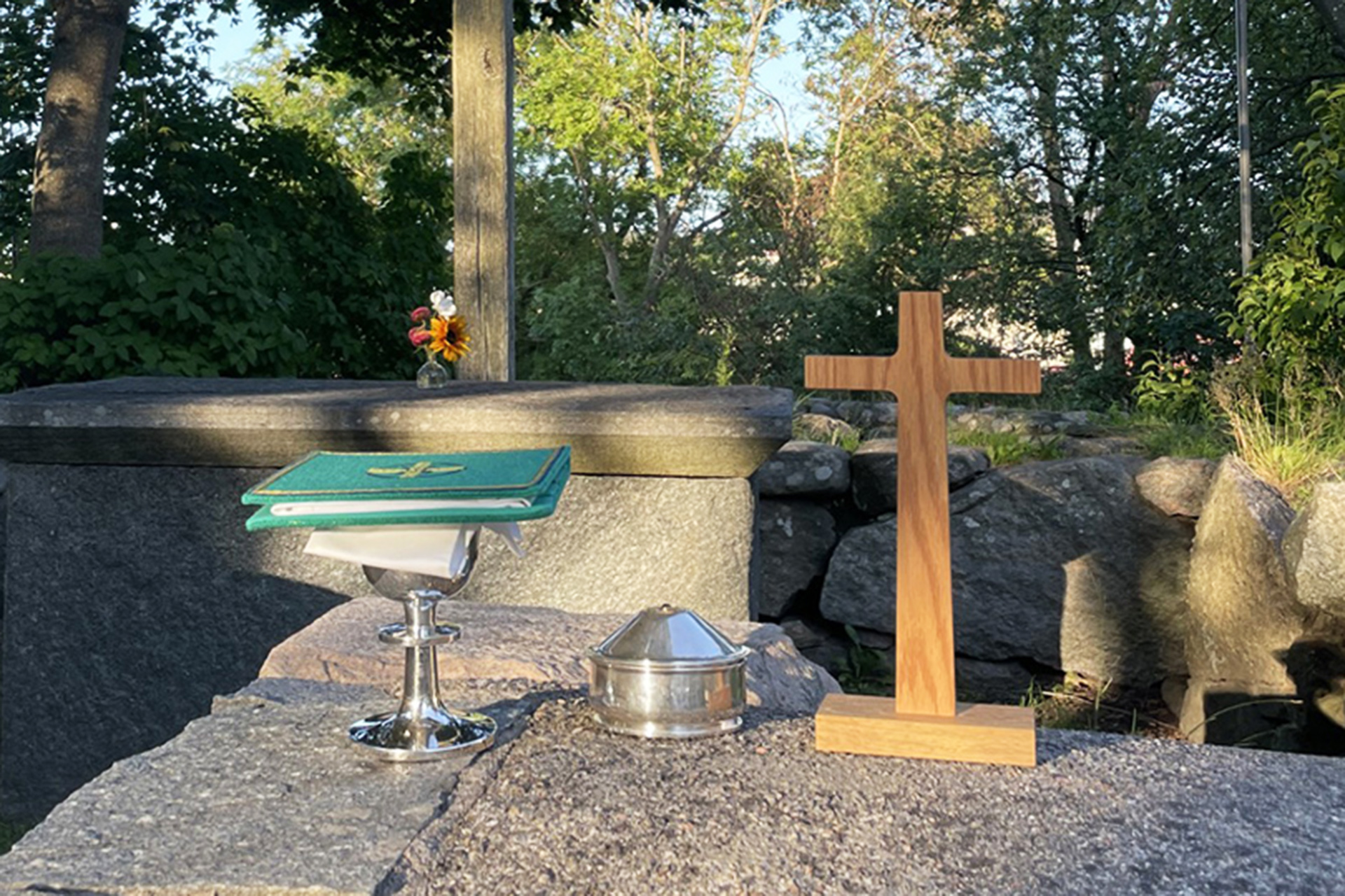 Nattvardssilver och kors på en stenmur.