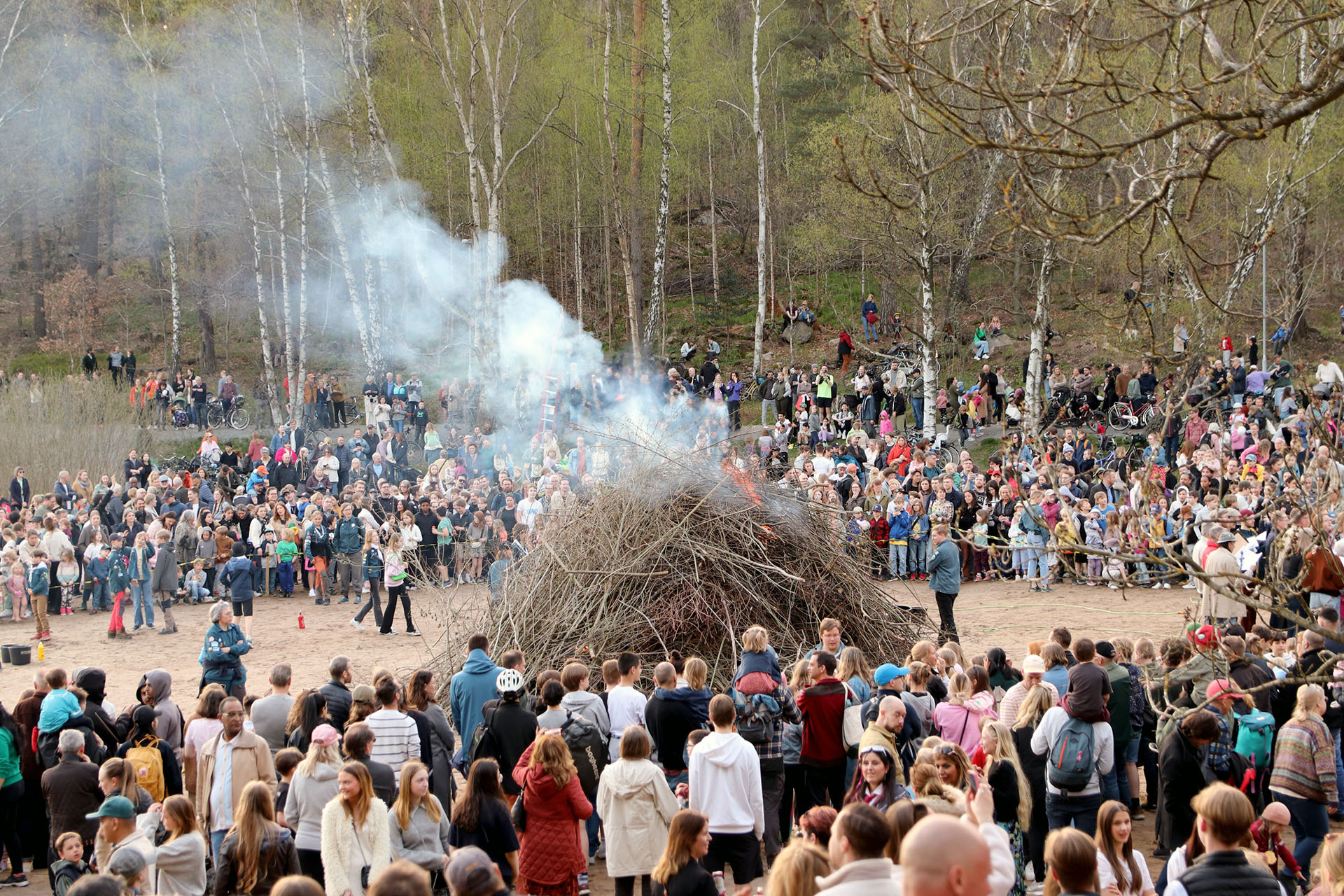 Människor står vid en brasa som tänds.