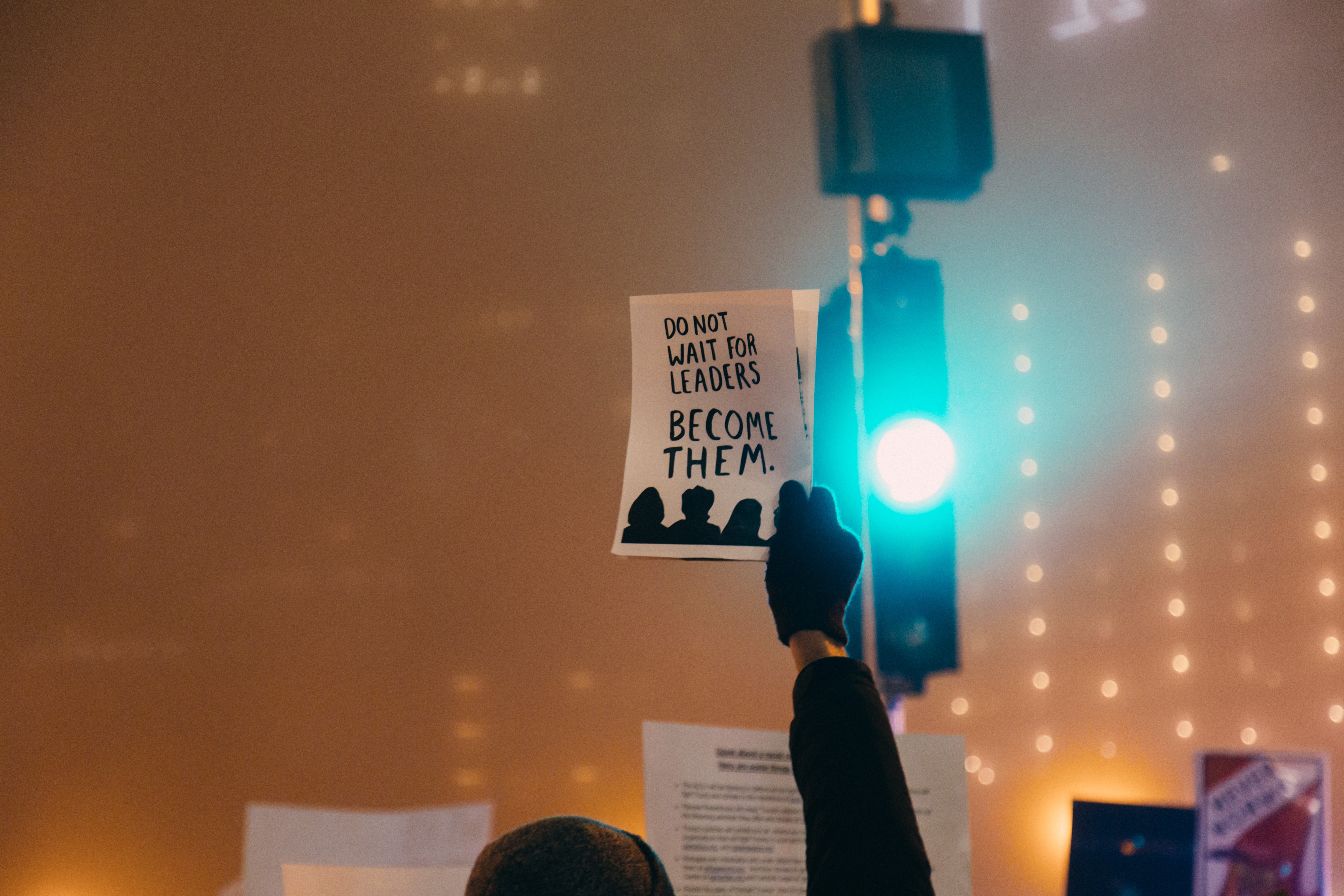 En hand håller en lapp med texten "Do not wait for leaders, become them"
