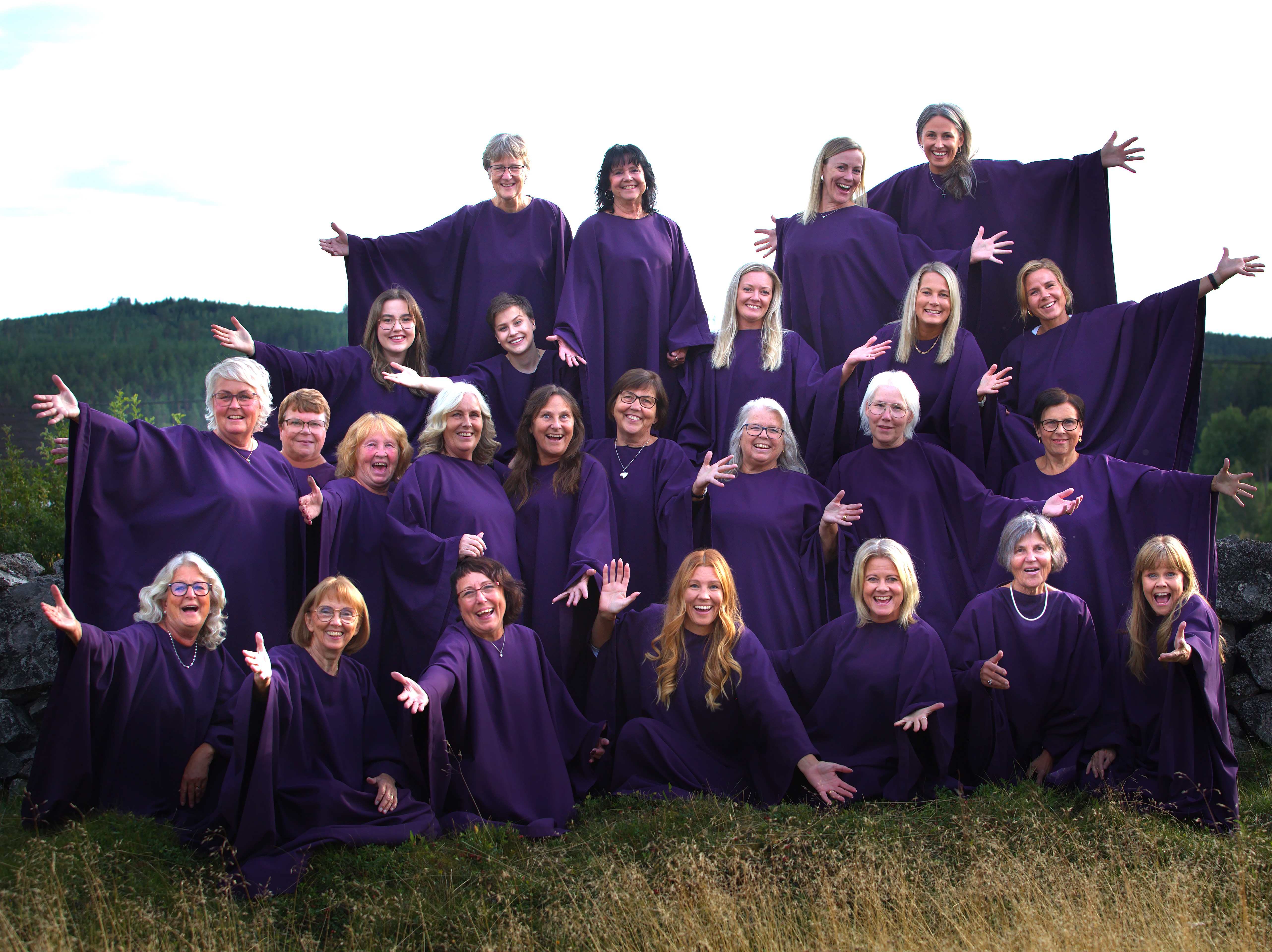 Kören Juniper Bay Gospel står med utsträckta händer utomhus vid en mur