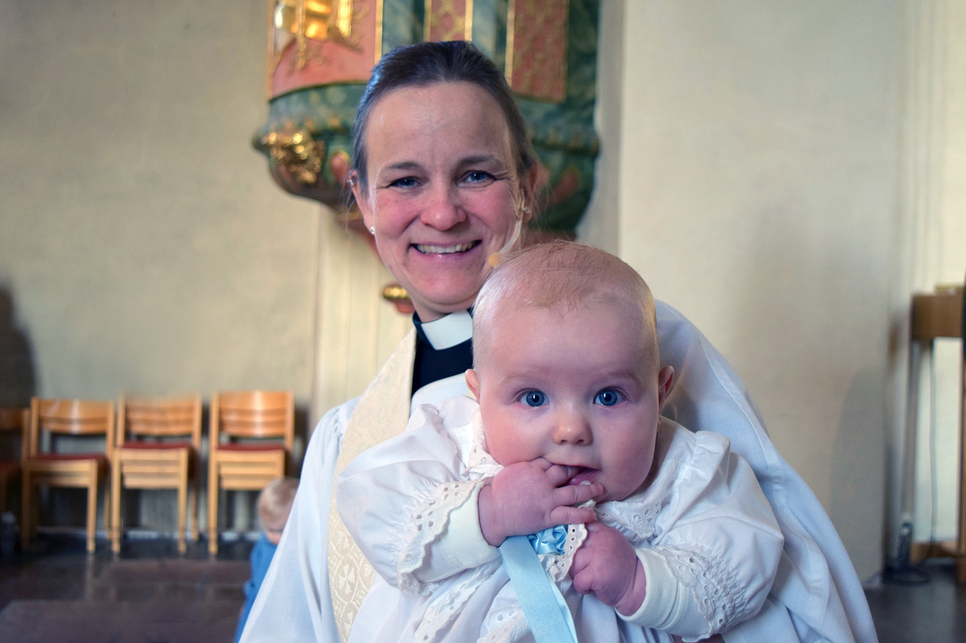 Prästen visar upp det nydöpta barnet