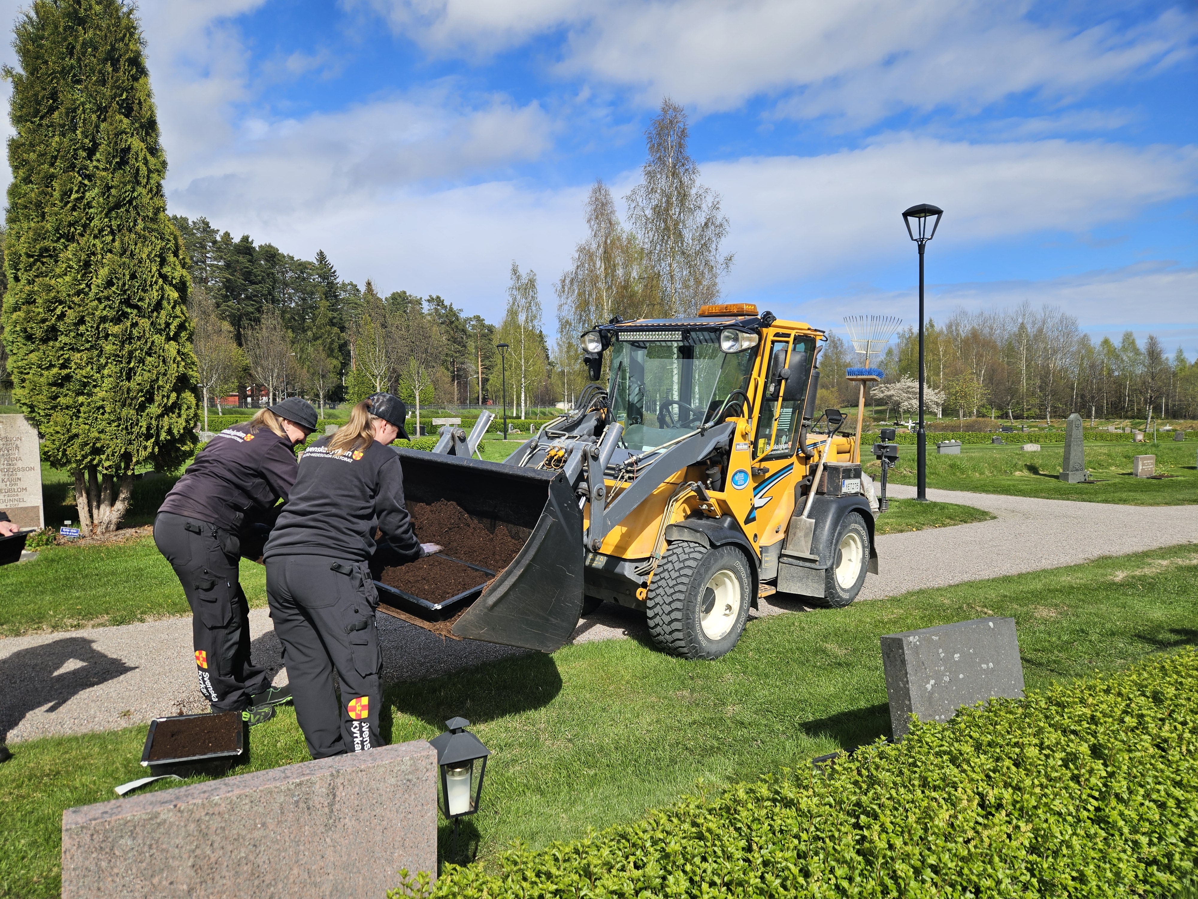 Kyrkogårdspersonal jordförbättrar på gravar.