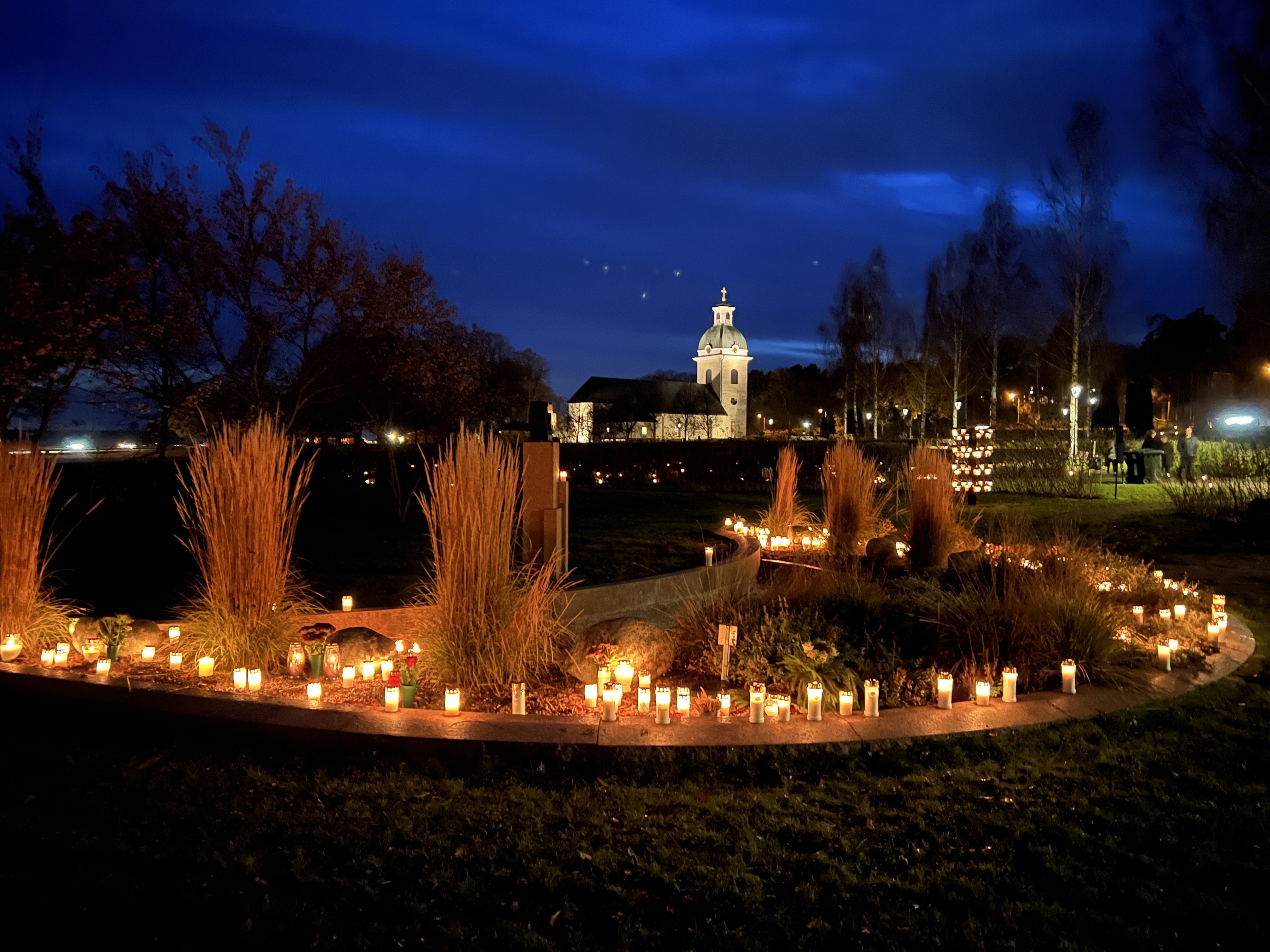 Valbo kyrkogård i allhelgonatid, upplyst av hundratals ljus i den mörka kvällen.