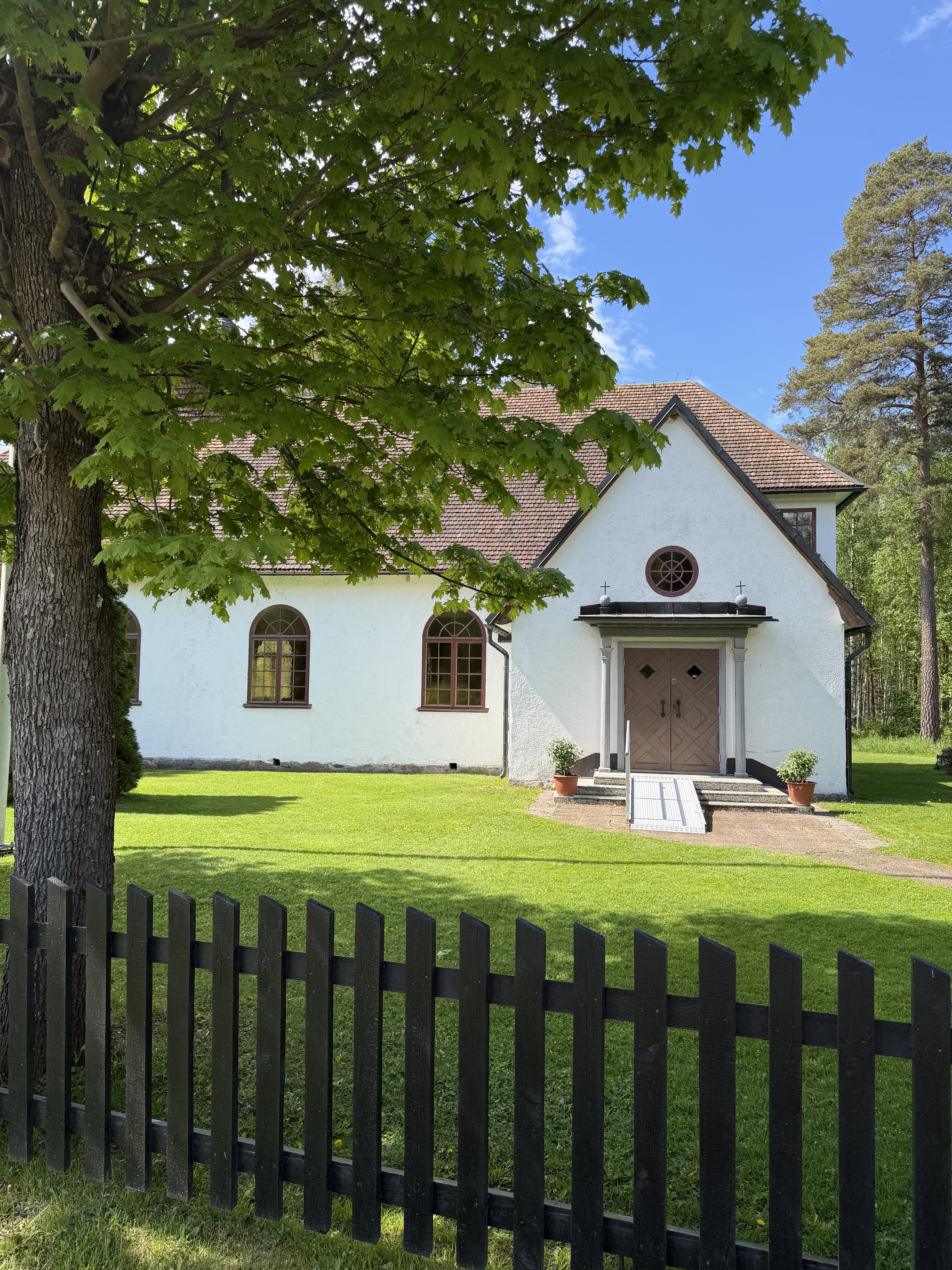 Den lilla vita Ansgariikyrkan inbäddad i grönska.