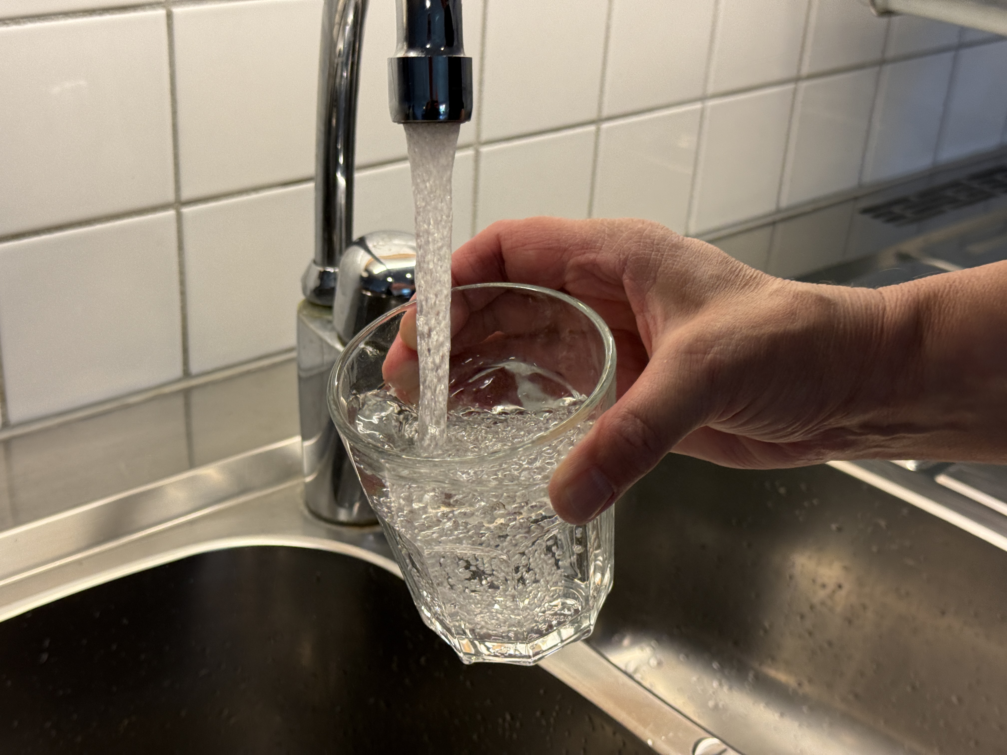 Ett glas som fylls med vatten från en vattenkran