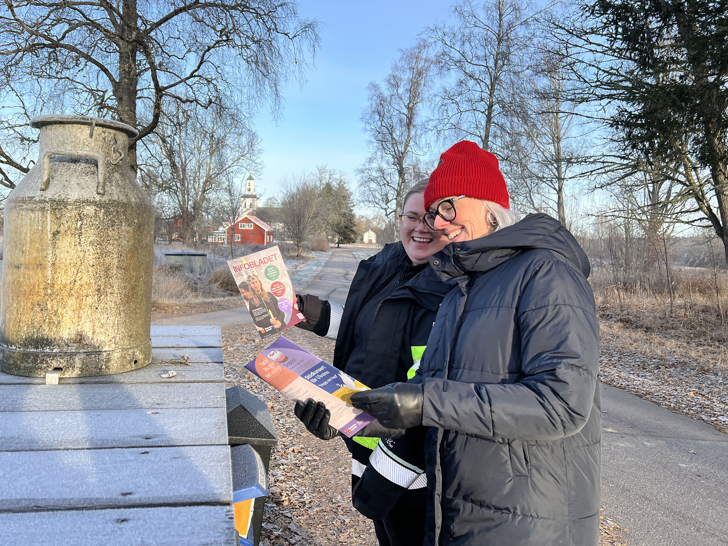 Två kvinnor läser Infobladet vid postlådan.