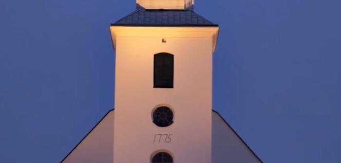 Hedesunda kyrka med adventsgranar i skymningen.