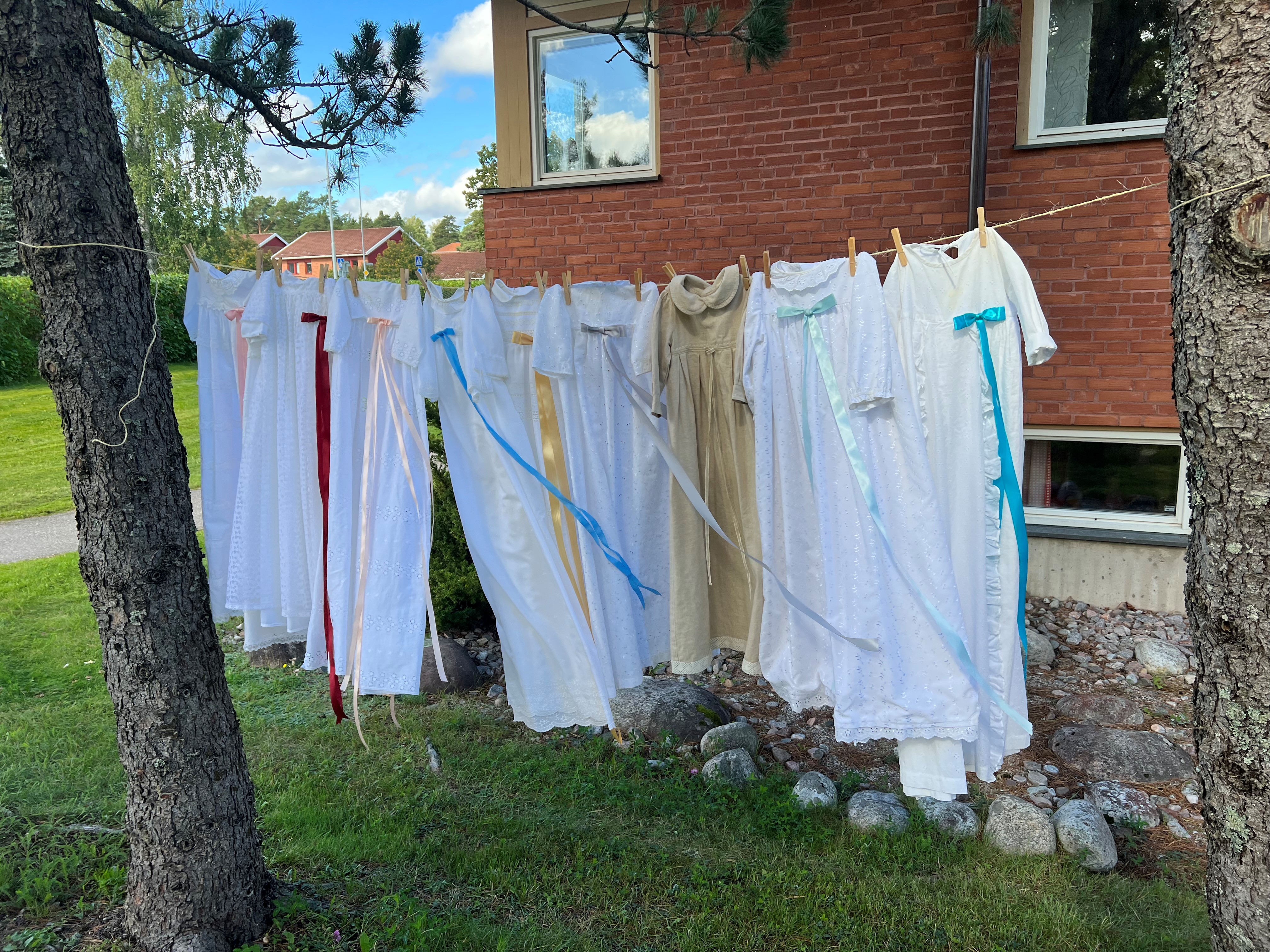 Pastoratets dopklänningar hänger på ett klädstreck i sommarvinden.