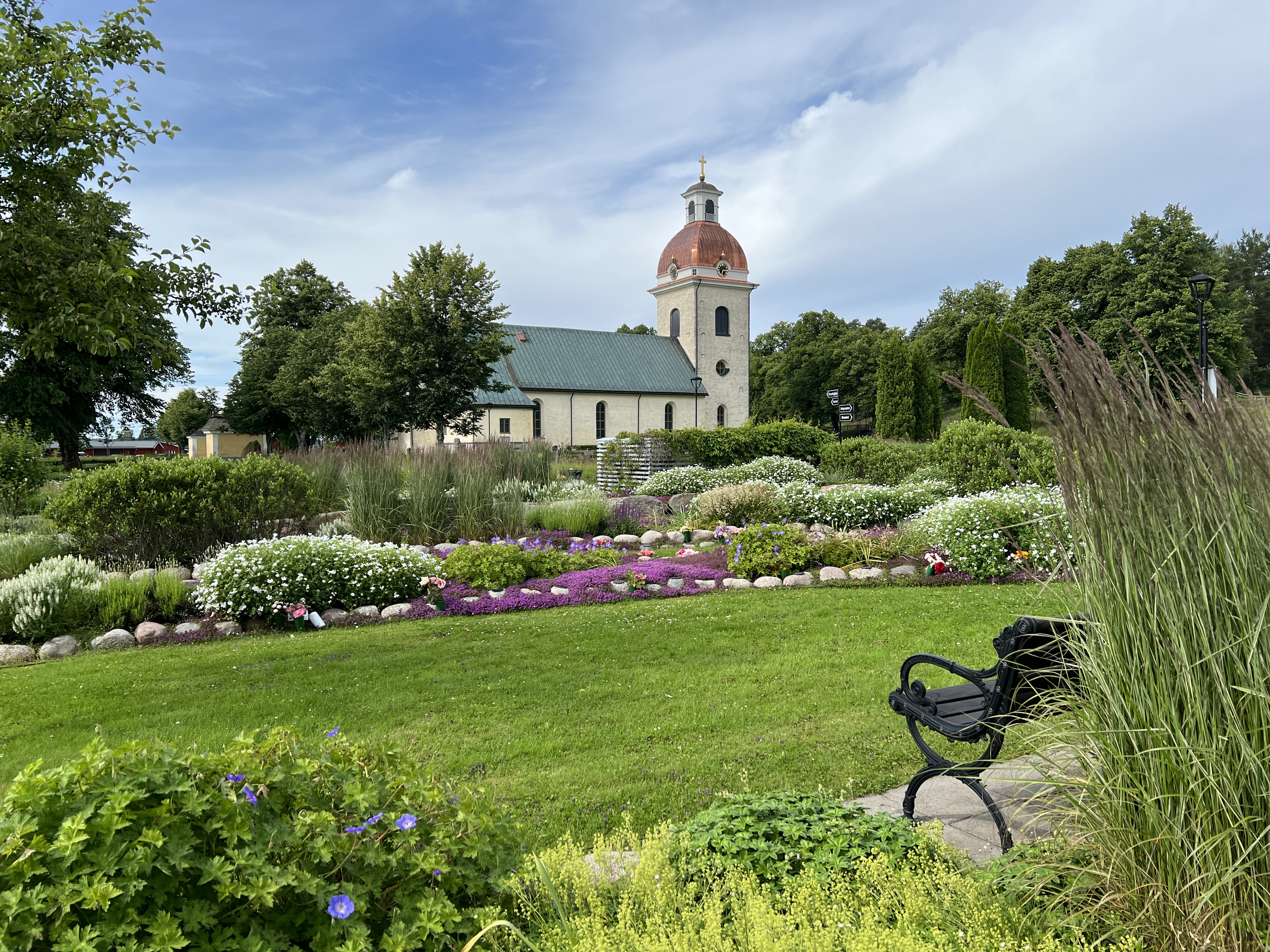 Valbo kyrka med den vackra minneslunden i förgrunden.