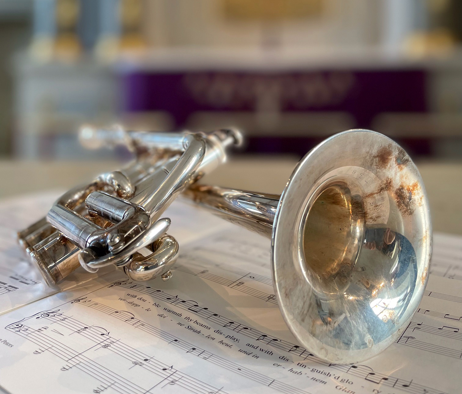 Silvrig trumpet med notblad under, utanpå ett altare